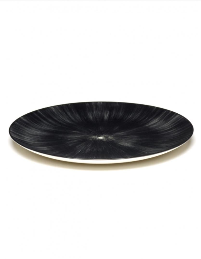 Set of two 28 centimeter hand-painted porcelain plates from Ann Demeulemeester. A black matte glaze on the outside with a glossy off-white glaze on the inside. The contrast between matte and glossy, but also the contrast between black and off-white,