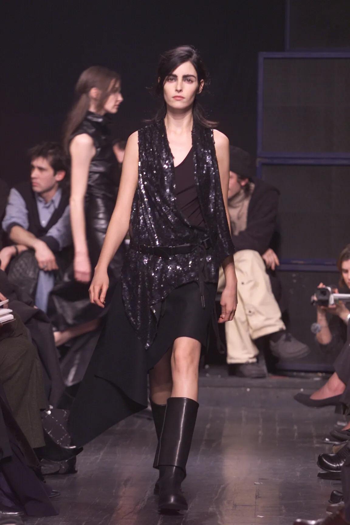 Dieses skulpturale Pailletten-Top ist ein seltenes und auffälliges Stück aus der Herbst/Winter 2000 Laufsteg-Kollektion von Ann Demeulemeester. Es ist eine Meisterklasse in dekonstruierter Eleganz und strukturellem Kontrast. Das in Belgien aus 100 %