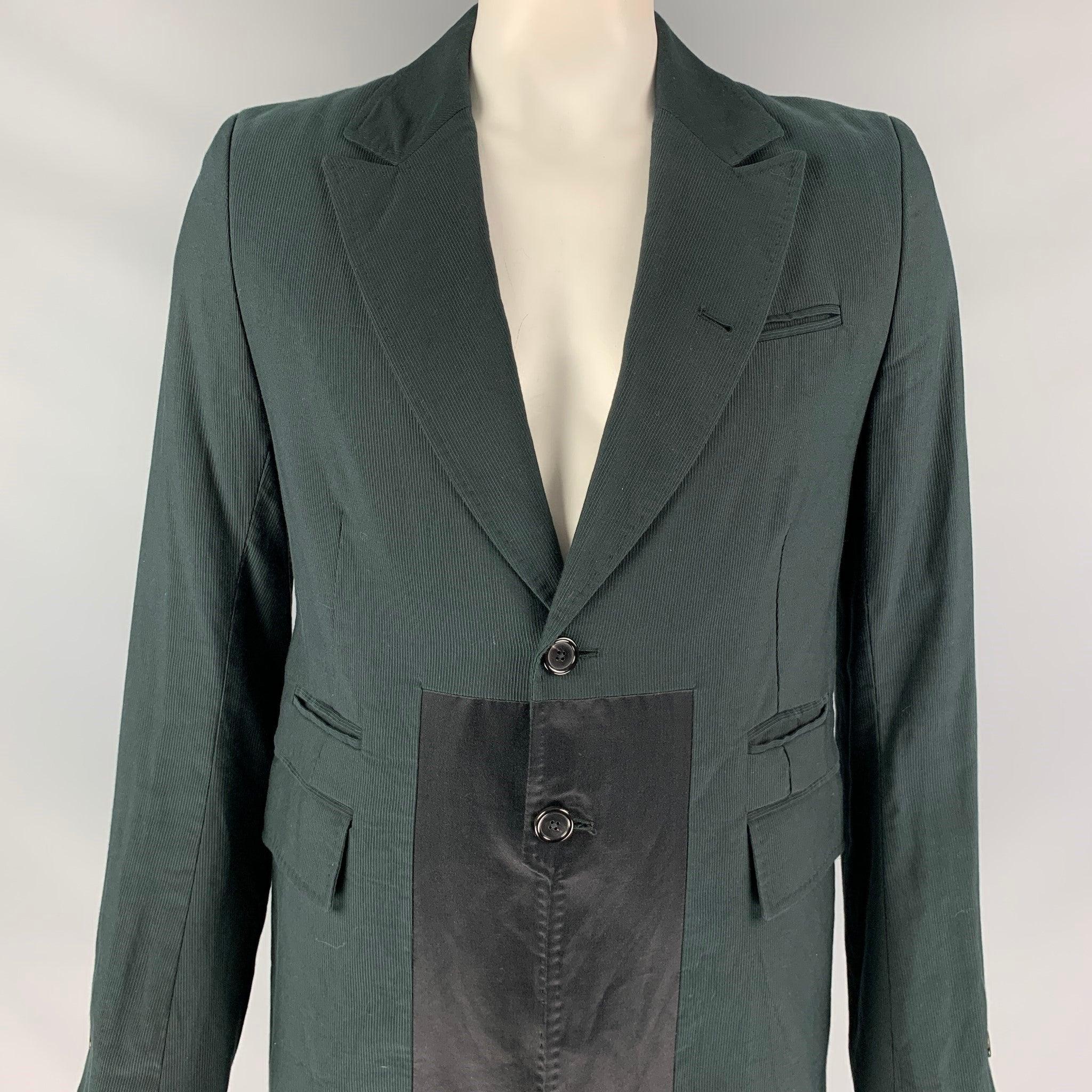 ANN DEMEULEMEESTER coat comes in a charcoal cotton with a front black panel detail featuring a peak lapel, front pockets, full liner, back slit, buttoned sleeve design, and a two button closure. Made in Italy.
Very Good
Pre-Owned Condition.
