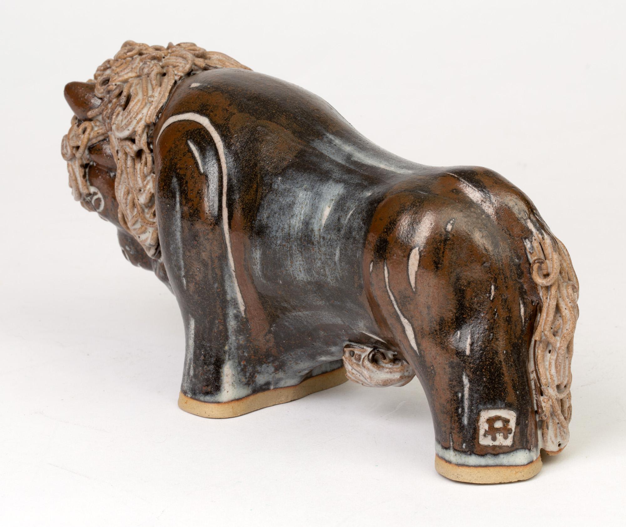 A stylish sculptural Studio Pottery of a bison made by Ann & John Farquharson and dating to the later 20th or early 21st century. The standing figure is hand formed with piped clay to its tail, under side and head decorated in a natural salt like