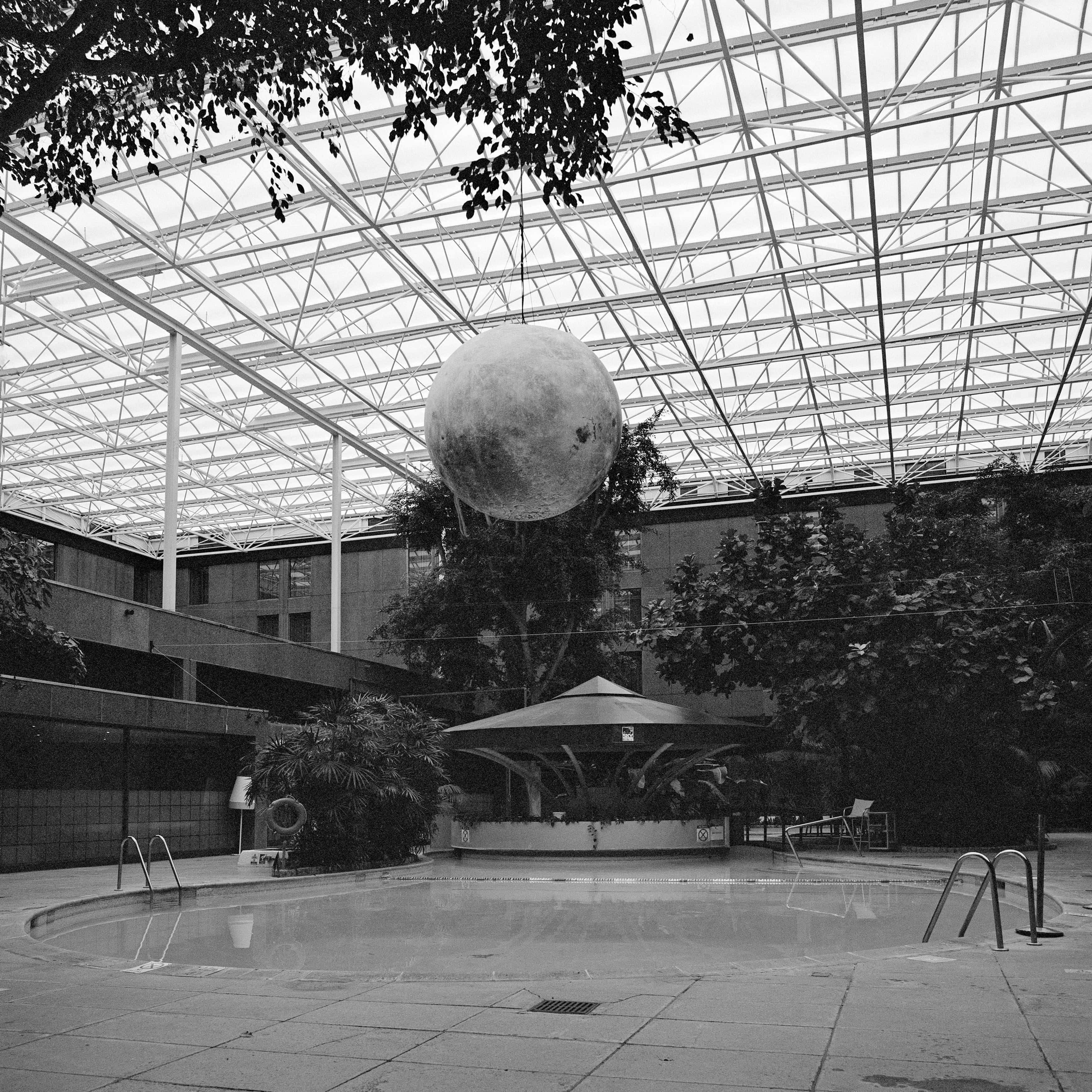 Fotografia architettonica quadrata in bianco e nero: Piscina d'albergo con sfera lunare