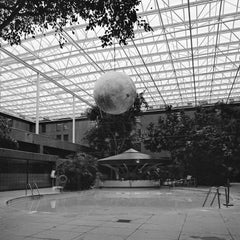 Photographie d'architecture carrée en noir et blanc : Piscine d'hôtel avec sphère lunaire