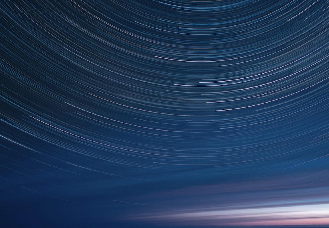 Deep blue night photo of star-trails. Black frame, museum glass - Photograph by Anna Dobrovolskaya-Mints
