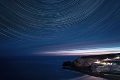 Deep blue night photo of star-trails. Black frame, museum glass