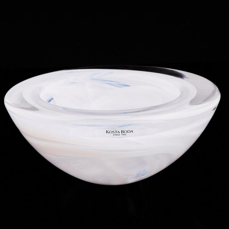 A Kosta Boda bowl by Anna Ehrner made from 1981 to 1989 in Kosta, Sweden.
The bowl features white and pale blue smoke like swirls set within thick clear glass. Acid etched stencil mark on base.
Type: lead art glass

Never having been regarded a