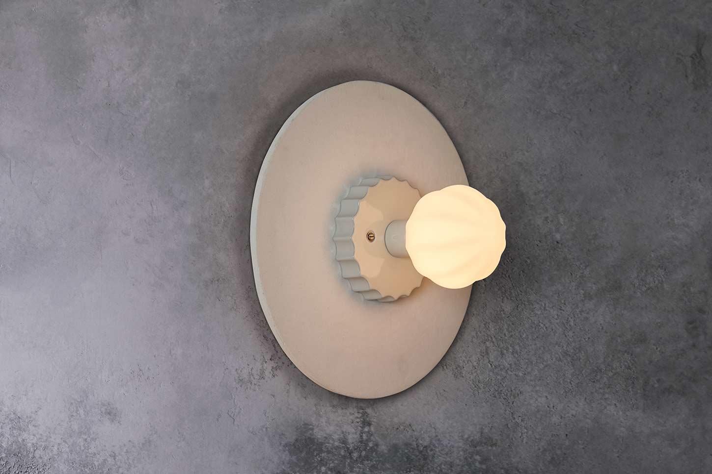 Composed of hand blown ridged glass, a glazed scalloped puck, and topped off with a large unglazed ceramic disc. The textural differences are picked up beautifully by the light. 