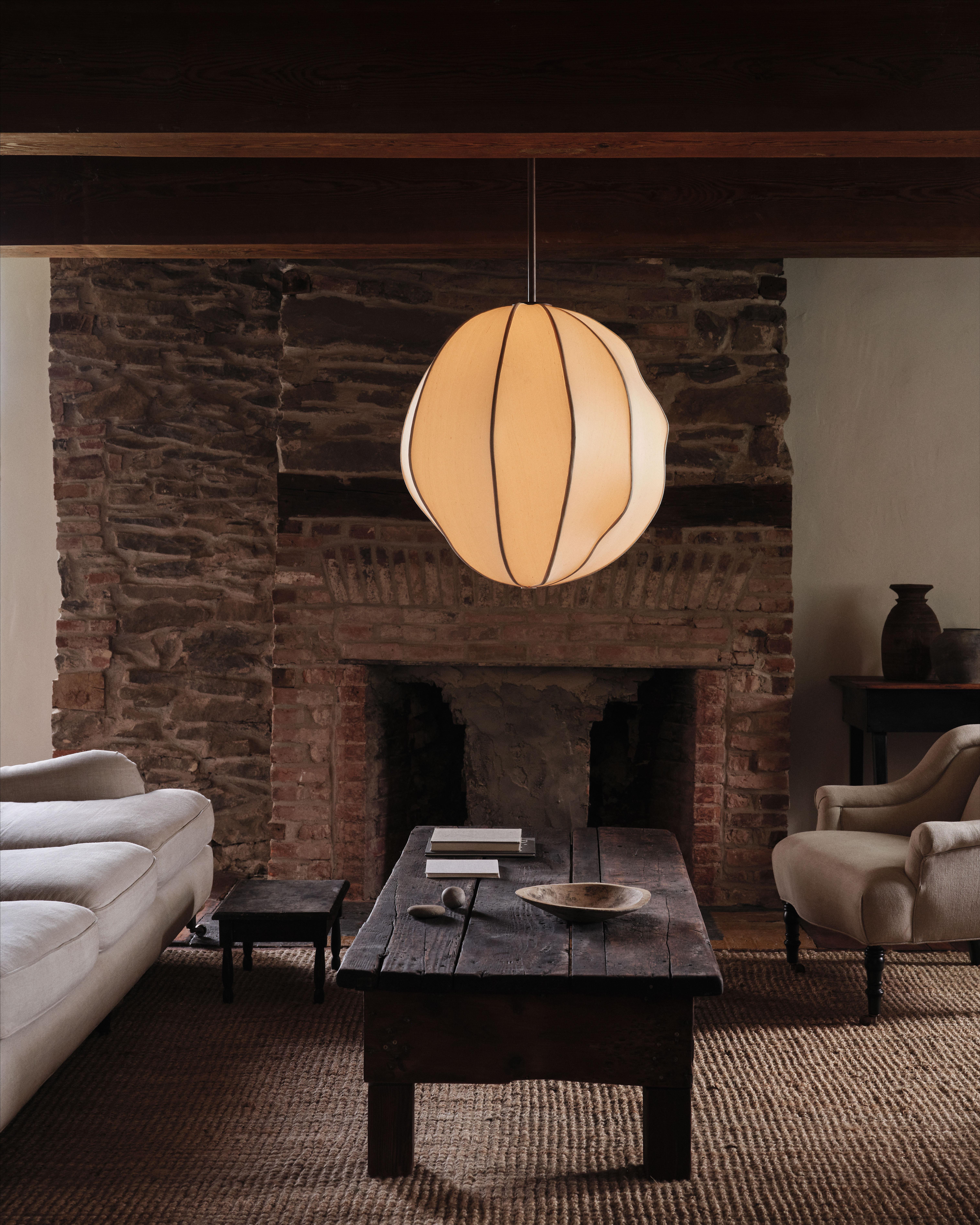A perforated hardwood post stretches from floor to ceiling, allowing the lamp armature to be moved up or down to the desired height. A hand-upholstered silk globe is suspended from the end of the armature, providing a warm glow.

Materials: White