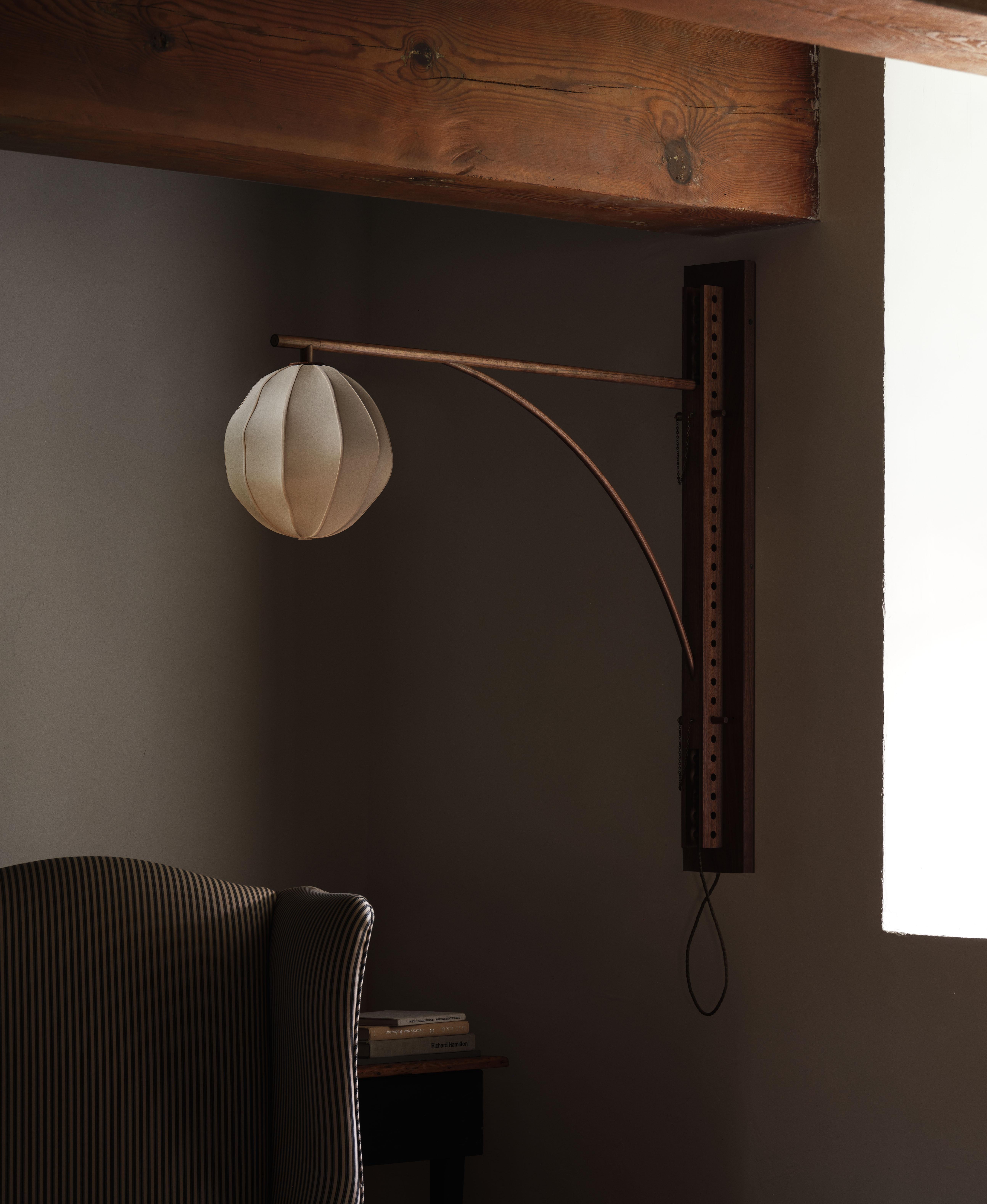 A perforated hardwood channel allows the lamp armature to be moved up or down to the desired height. A hand-upholstered silk globe is suspended from the end of the armature, providing a warm glow.

Materials: White Oak or Black Walnut with Silk