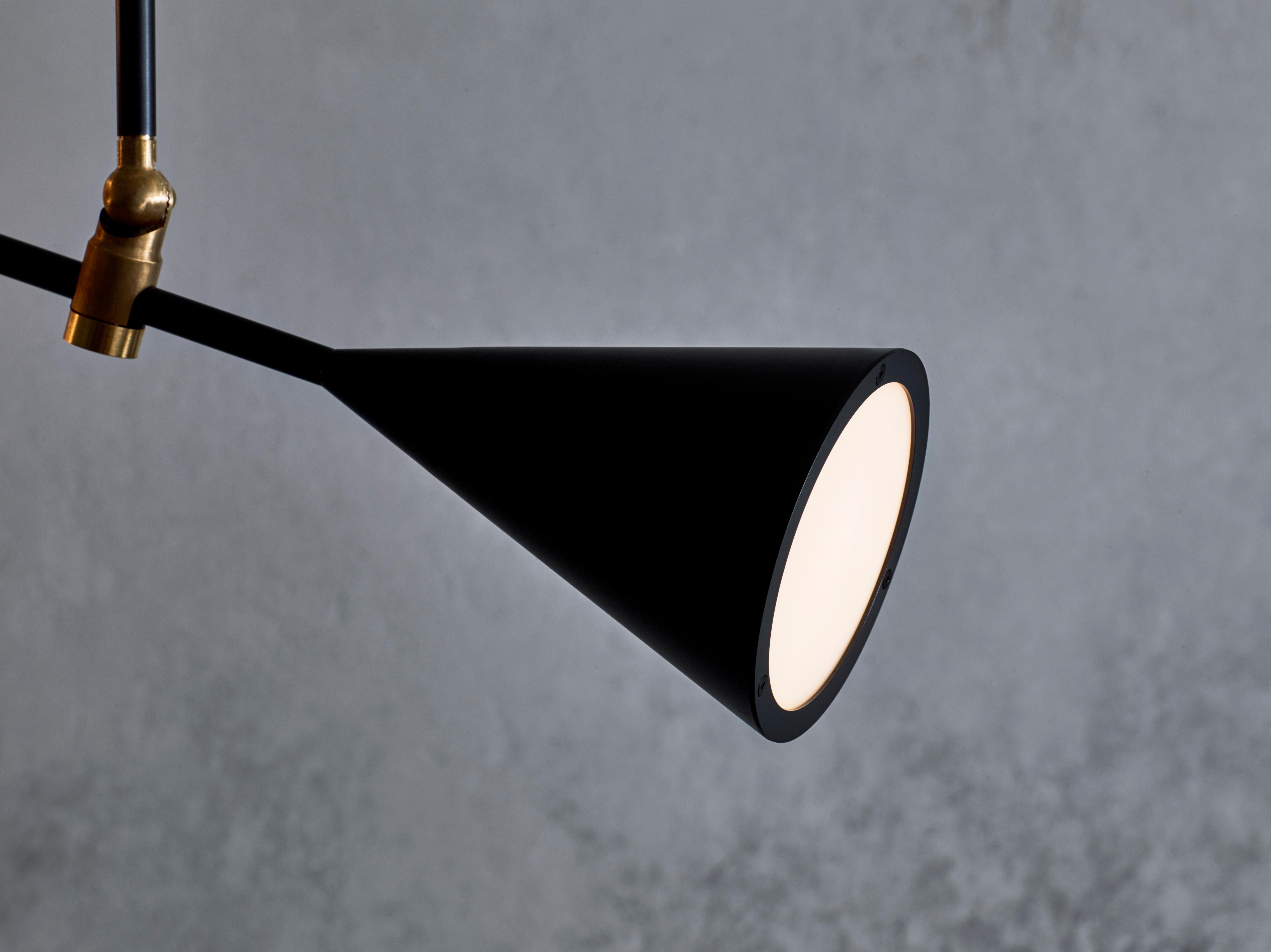 A conical light source at one end and a handblown matte white glass orb on the other hold this piece in balance. The central hinge mechanism allows adjustment of the fixture to any desired angle. Available in satin black (a rich warm black) and