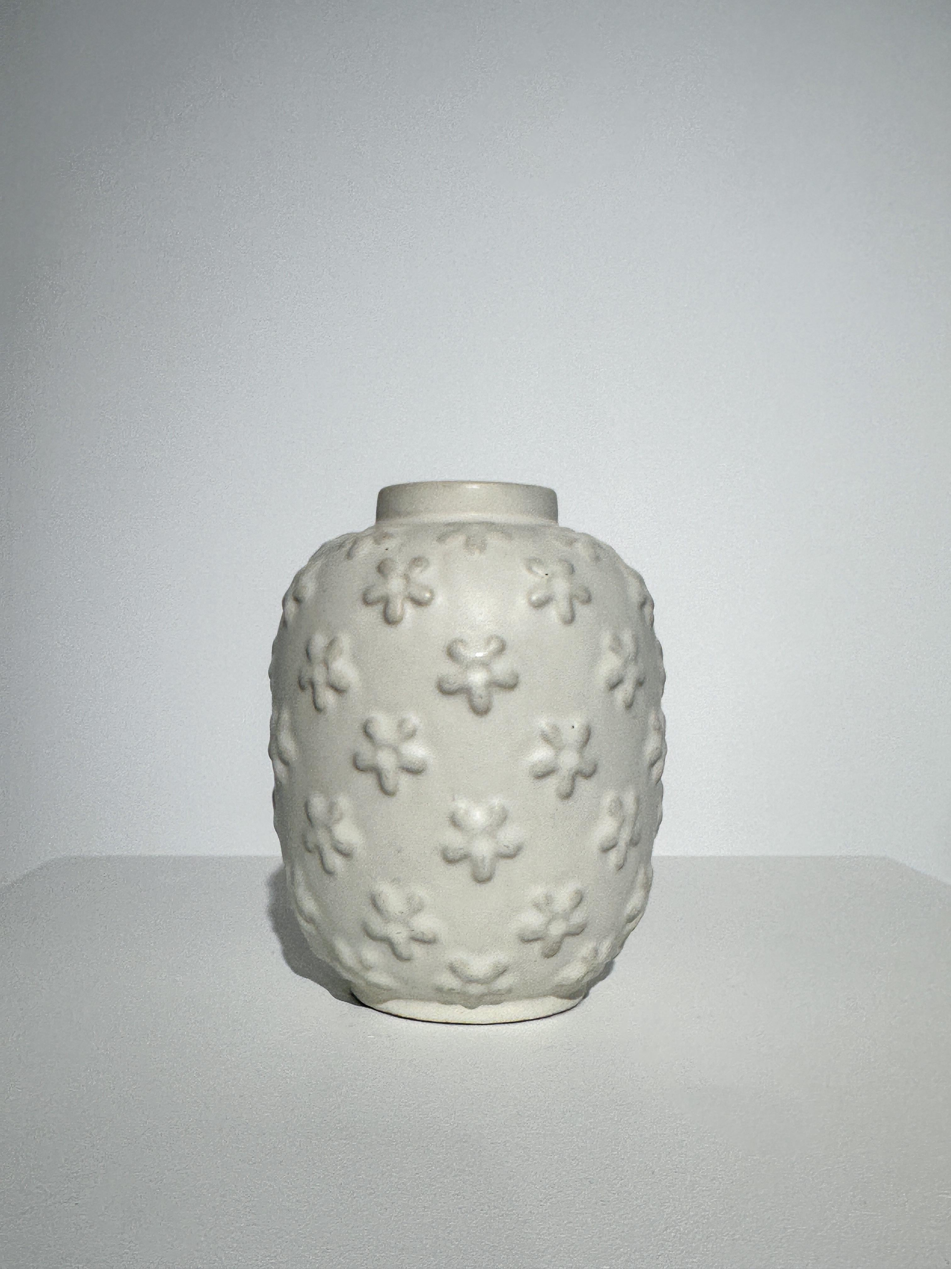 Rare and early Anna Lisa Thomson stoneware vase with relief decor, hand crafted at Upsala Ekeby in Sweden in the late 1930s to early 1940s.

Beautiful cream white color, shows some patina and small glazing defect on one of the flowers, see