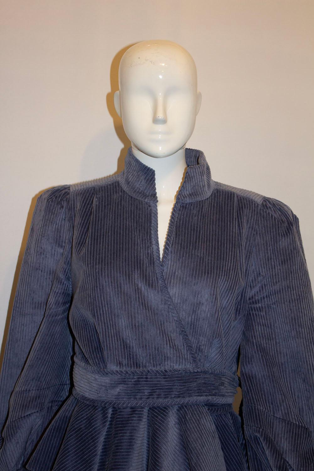 A wonderful jacket for Spring by leading British designer Anna Mason. The jacket is in a pretty blue/grey corduroy, and can be worn with the belt tied at the front or pulled through the loop and tied at the side. It has gathered sleaves, a stand up