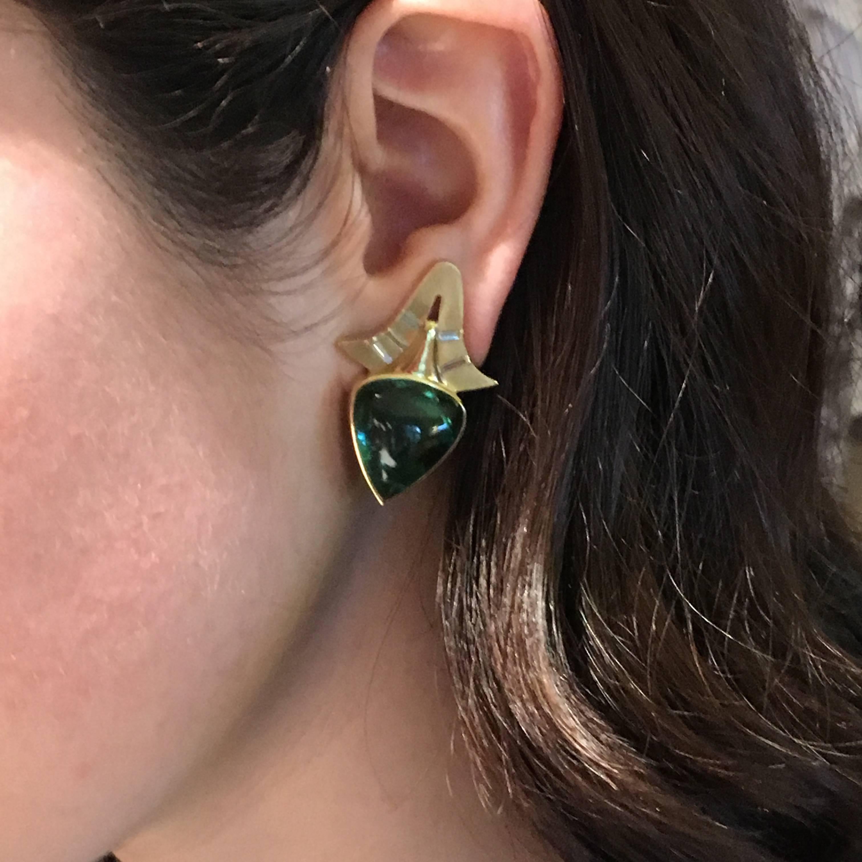 18ct yellow gold Dotaku earrings set with 29.64cts green tourmaline pear-shaped cabochons and 0.48ct baguette diamonds. The design developed from a drawing I made of a Japanese Buddhist bell, I was drawn to the elegant lines, negative shape,
