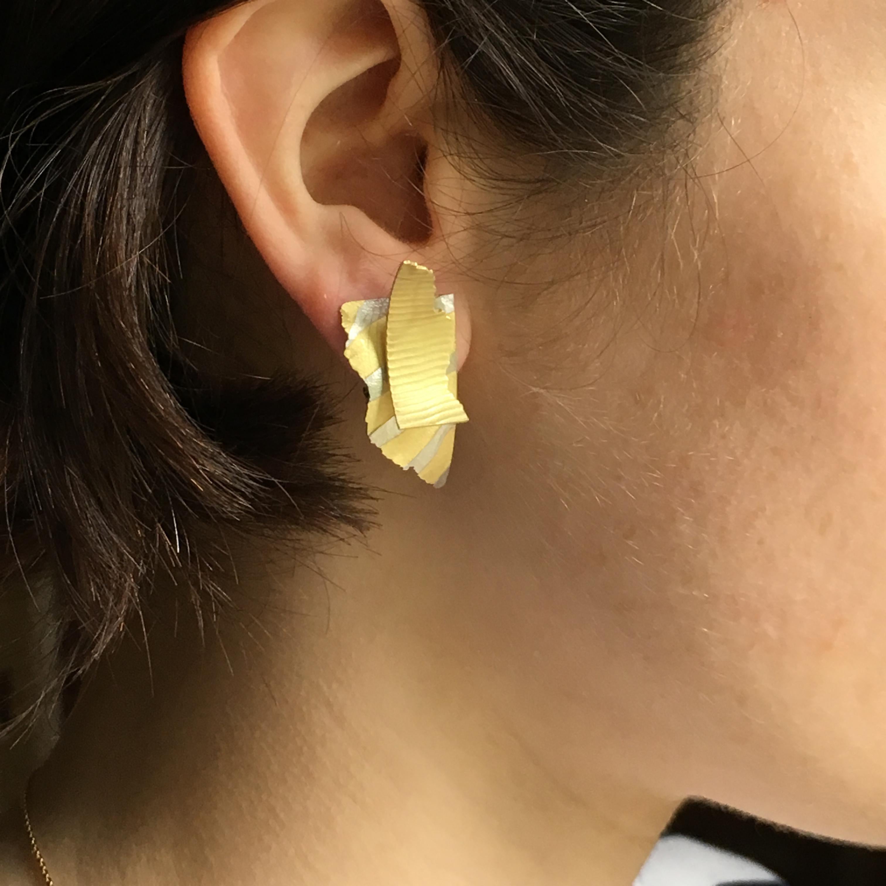 18ct yellow gold Cuttings earrings with a fused platinum inlay, impressed textures, and contrasting torn and straight edges. They resemble precious fragments placed one on top of the other as on a designer's mood board. The fittings are posts and