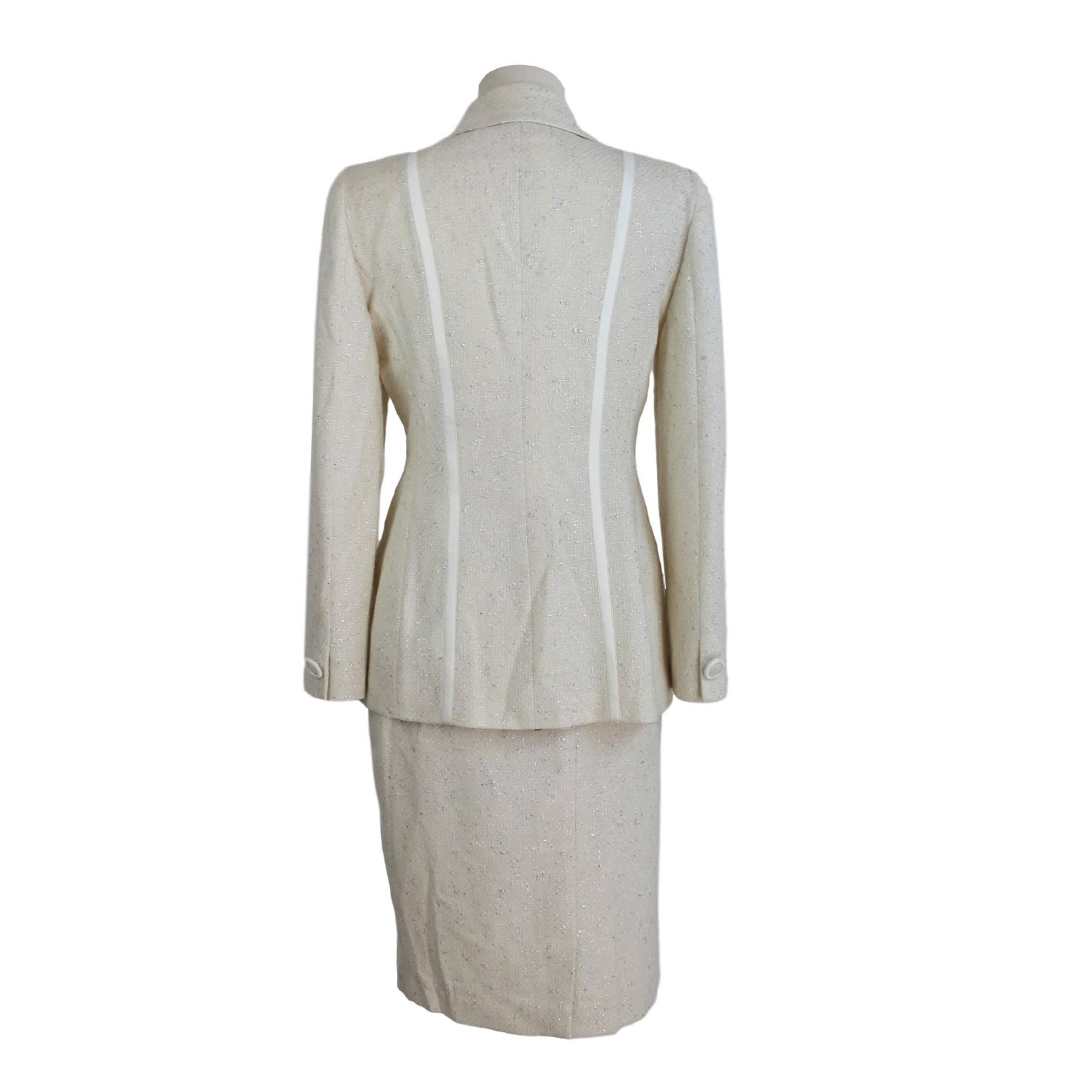 Annalisa Ferro elegant women's suit skirt. Suit consisting of jacket and skirt. White color with silver threads. The jacket with two buttons closure, two pockets on the sides. Along the satin pattern jacket. Long skirt on sheath knee. Made in Italy.