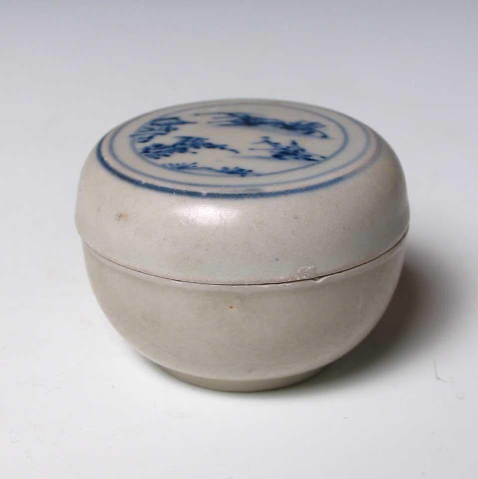Annamese Blue and White Ceramic Box, Chu Dau kiln, Vietnam, circa 1500. A ceramic covered flat top circular box with lid decoration in under glaze cobalt blue of a landscape scene containing trees, rocks and pavilion all within circular bands, the