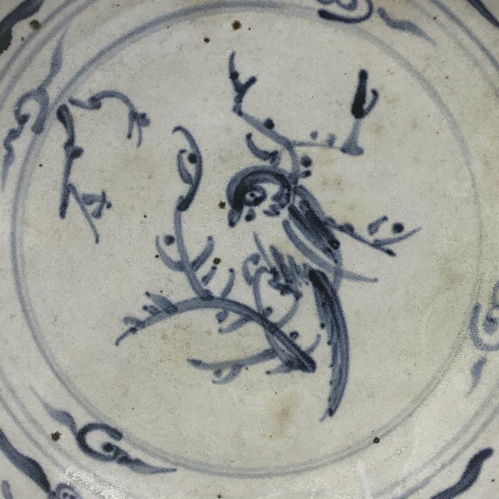 Annamese Blue and White Ceramic Dish, Bird Design, Chu Dau kiln, Vietnam, circa 1500. A sturdily potted plate with raised rim, decorated in under glaze cobalt blue of a parrot perched on a prunus branch on center surrounded by decorative bands of