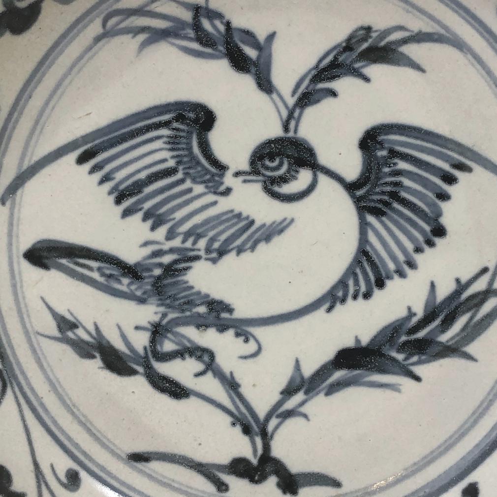 Annamese Blue and White Ceramic Dish, Bird Design, Hoi An Hoard, Chu Dau kiln, Vietnam, circa 1500. The sturdily potted form has a raised rim decorated in under glaze cobalt blue of a plump bird perched on a leafy bamboo branch on center, surrounded