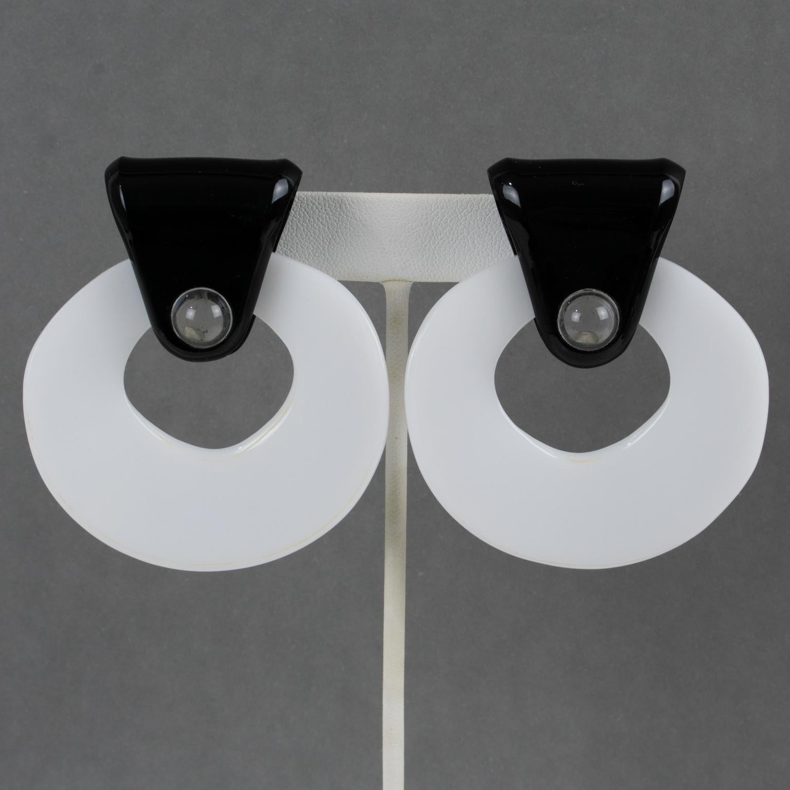 Anne & Frank Vigneri diseñaron estos raros e impresionantes pendientes de clip de Lucite de gran tamaño en la década de 1980. Presentan una aldaba geométrica con forma colgante, acentuada con un elemento colgante blanco y contrastada con cierres
