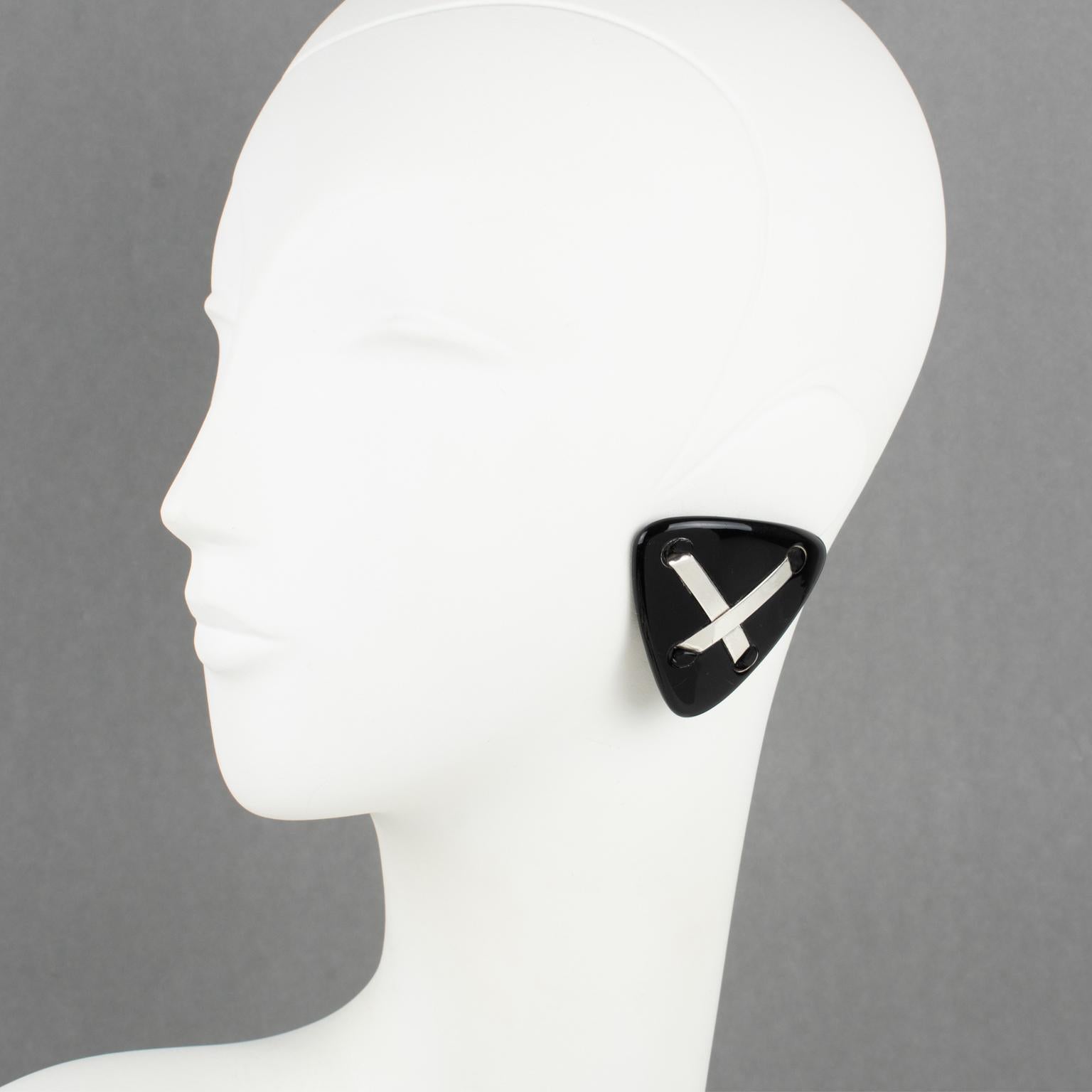 Anne and Frank Vigneri designed these stunning Lucite clip-on earrings in the 1980s. The geometric triangle design features a black Lucite element, topped with sterling silver crossed bands. The rare earrings are unsigned, but the exclusive French