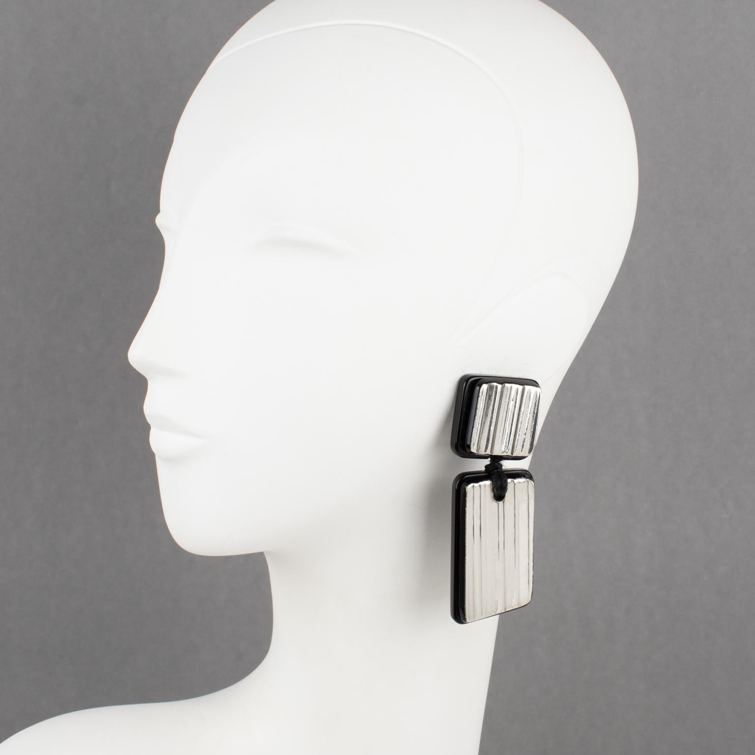 Anne and Frank Vigneri designed these spectacular Lucite clip-on earrings in the 1980s. The geometric design features a black Lucite base background topped with sterling silver carved and striped elements. The earrings are unsigned, but the special