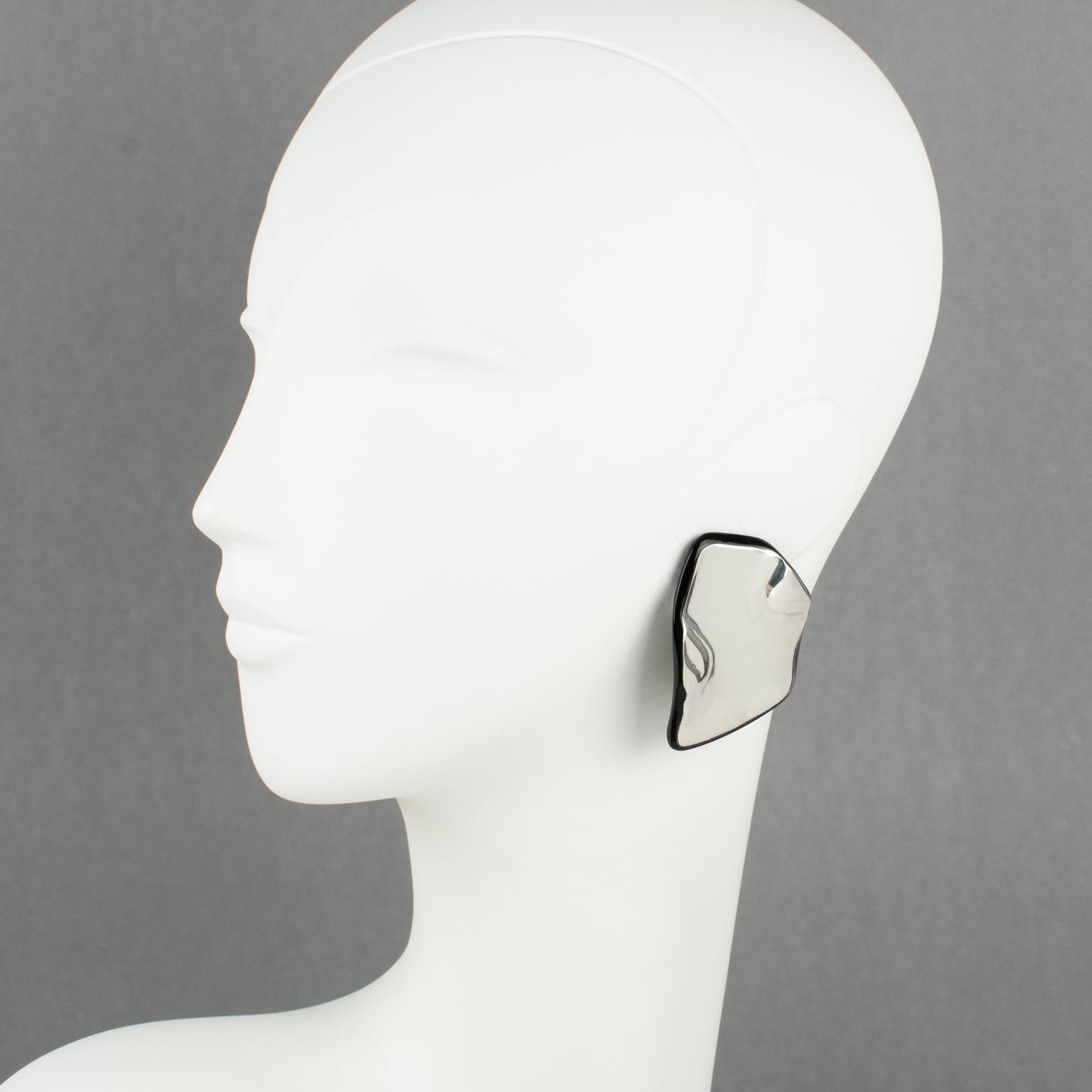 Anne and Frank Vigneri designed these stunning Lucite clip-on earrings in the 1980s. The freeform design features a black Lucite base, topped with a sterling silver embossed element. The earrings are unsigned, but the special French clip-back is an