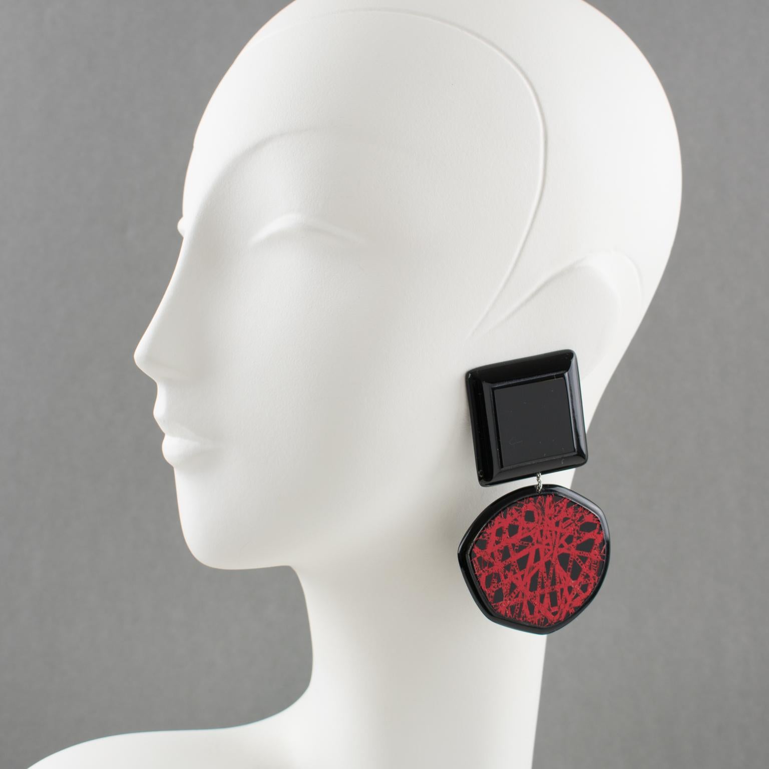 Charming Anne and Frank Vigneri Lucite clip-on earrings. Oversized geometric dangling design with square and free-form disc shape in licorice black Lucite or resin. The disc is ornate with a textured red design similar to intersecting lines. No