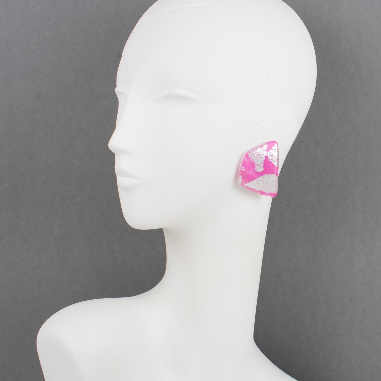 These stunning Anne and Frank Vigneri Lucite clip-on earrings feature a dimensional curved geometric design. The earrings are built with multilayer Lucite, white background topped with bubblegum pink Lucite with embedded silver foil inclusions.