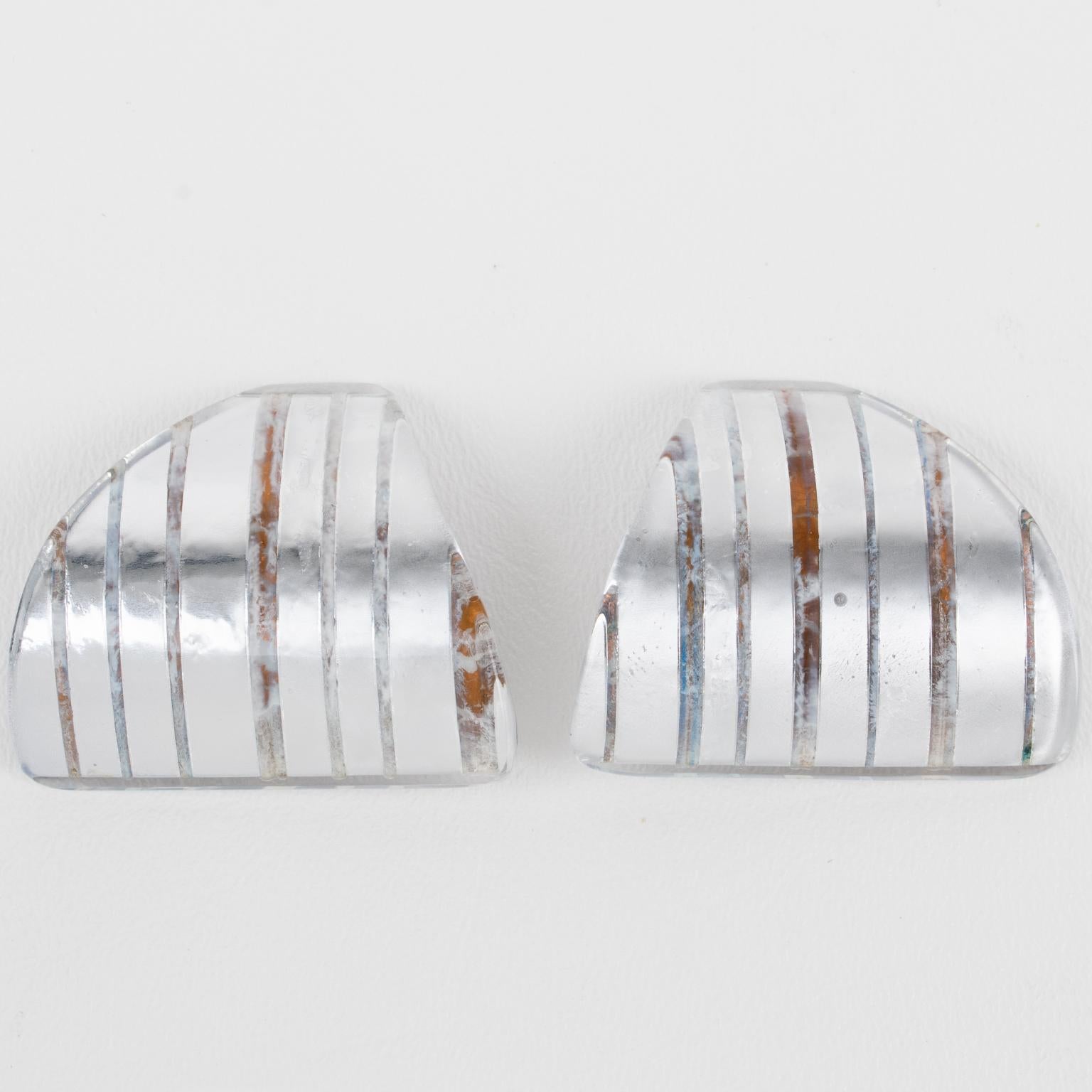 These stunning Anne and Frank Vigneri Lucite clip-on earrings feature a dimensional curved triangle design. The earrings are crafted from multilayer Lucite, featuring a white-colored background topped with transparent Lucite that incorporates