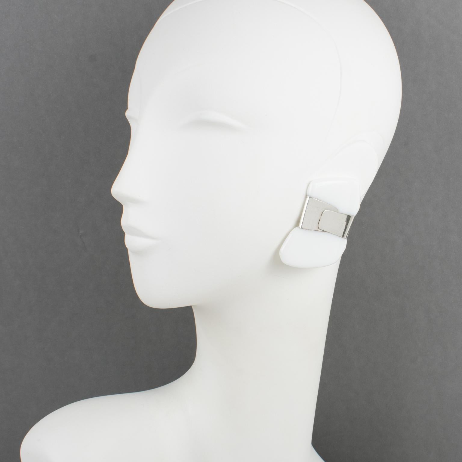 These elegant oversized Lucite clip-on earrings were designed by Anne and Frank Vigneri in the 1980s. The geometric, futuristic shape features a white Lucite element wrapped in a sterling silver band. The earrings are unsigned, but the specific