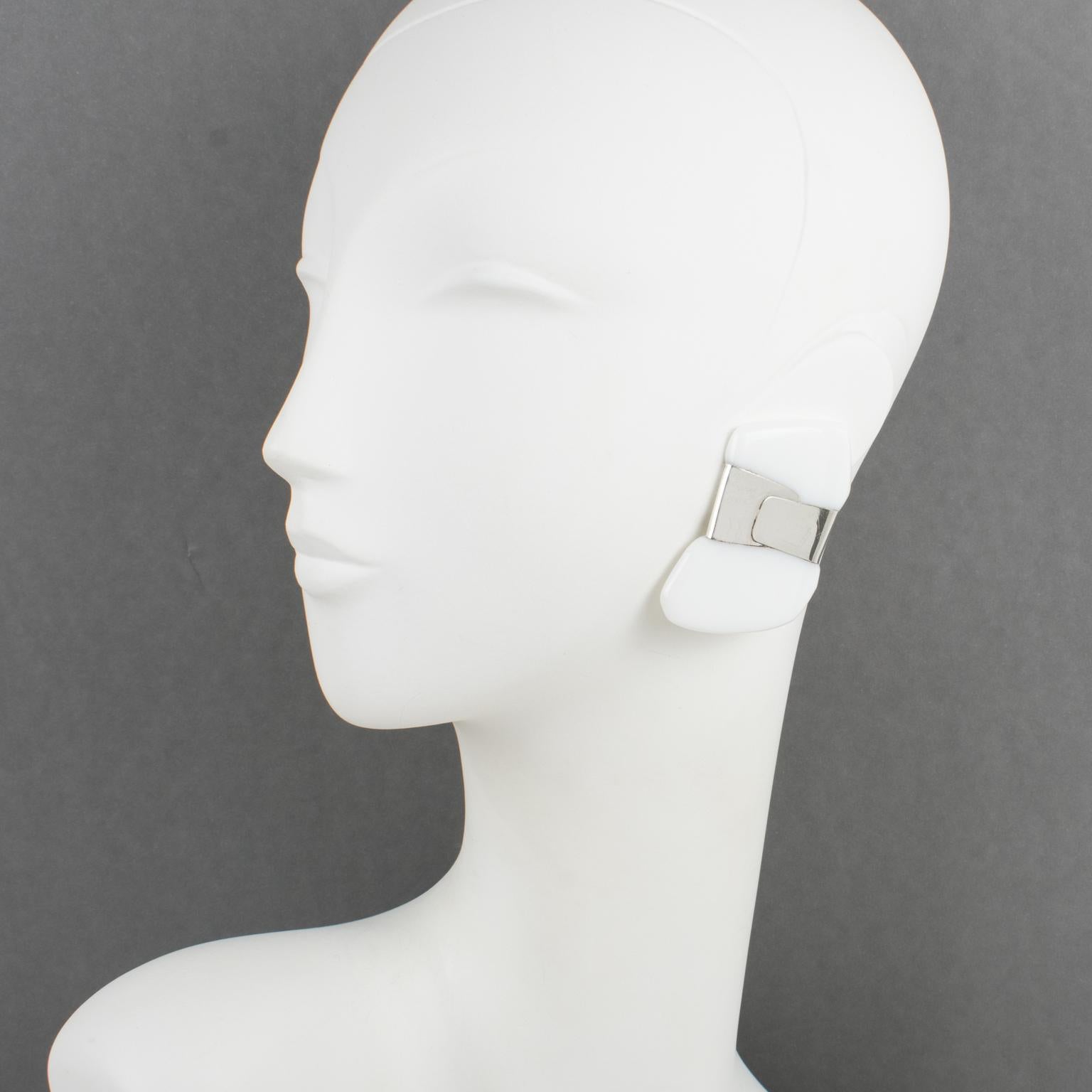 Anne and Frank Vigneri designed these rare elegant oversized Lucite clip-on earrings in the 1980s. The geometric, futuristic shape features a white Lucite element wrapped in a sterling silver band. The earrings are unsigned, but the characteristic