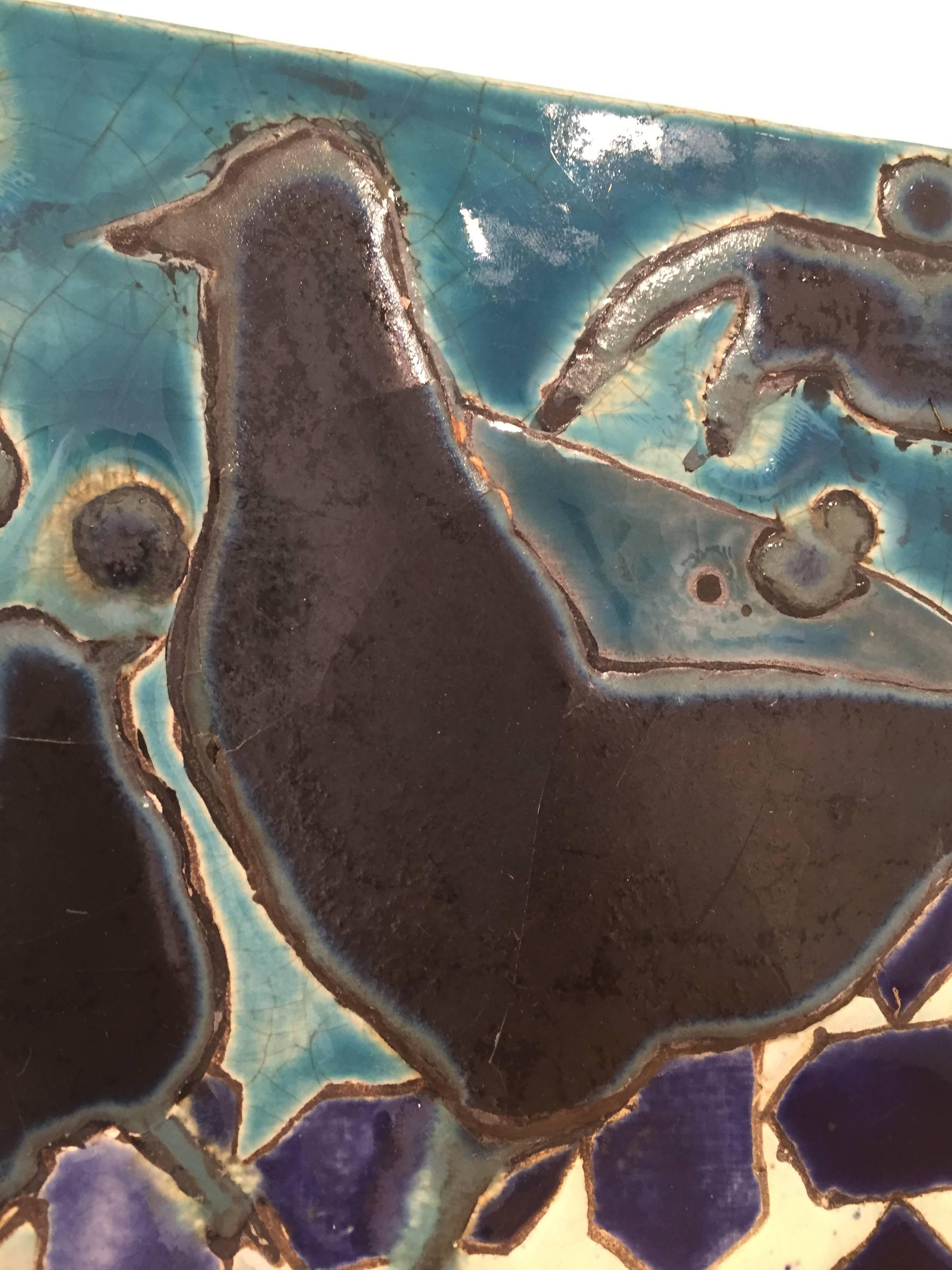 Abstract ceramic wall sculpture on panel of black birds and mosaic blue and teal tile
13 x 13 inches
Earthenware, ceramic glazes on panel

This contemporary hanging ceramic tile was crafted by Saratoga, NY-based artist Anne Francey. The composition