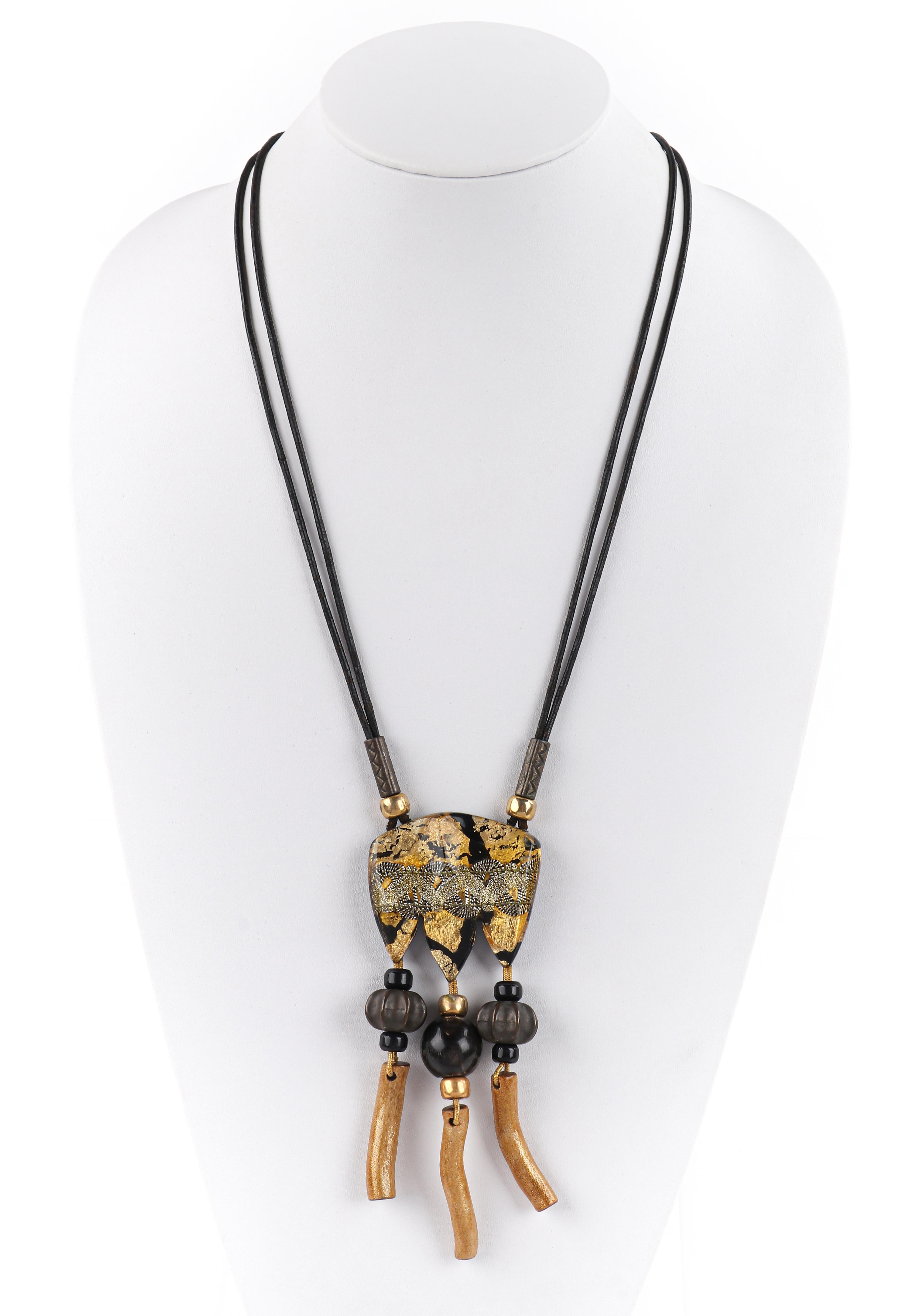 ANNE & FRANK VIGNERI Black Gold Metallic Beaded Lucite Art Pendant Cord Necklace
 
Brand / Manufacturer: Vigneri
Circa: 1980s-1990s
Style: Pendant necklace
Color(s): Shades of black, gold, brown, silver
Unmarked Material (feel of): Pendant: Lucite;