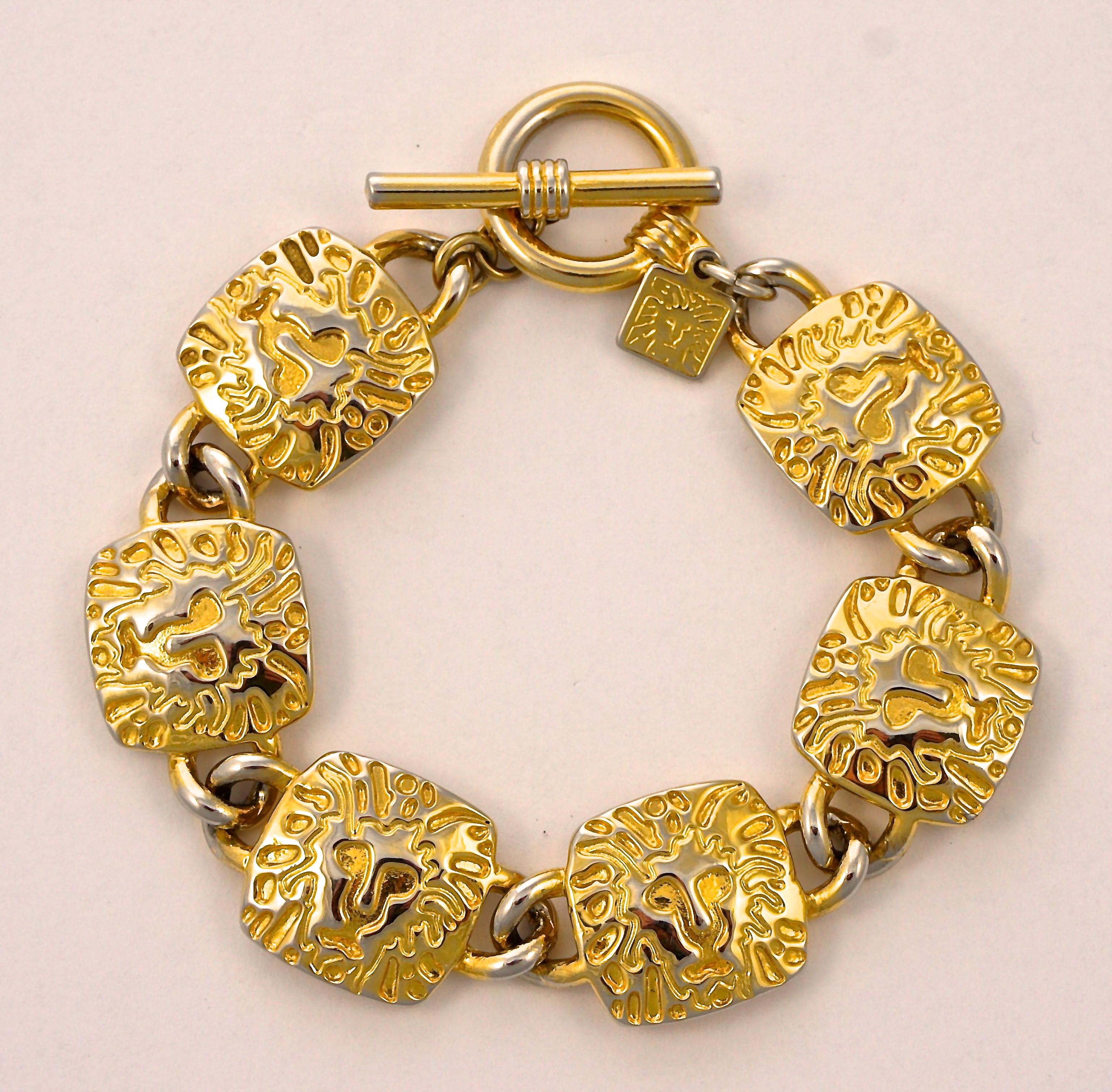 Bracciale con maglie a forma di leone e orecchini a goccia a forma di leone placcati in oro di Anne Klein. Il bracciale misura 19,5 cm di lunghezza per 1,7 cm di larghezza, ha una chiusura ad alamaro e il logo del leone di Anne Klein. Gli orecchini