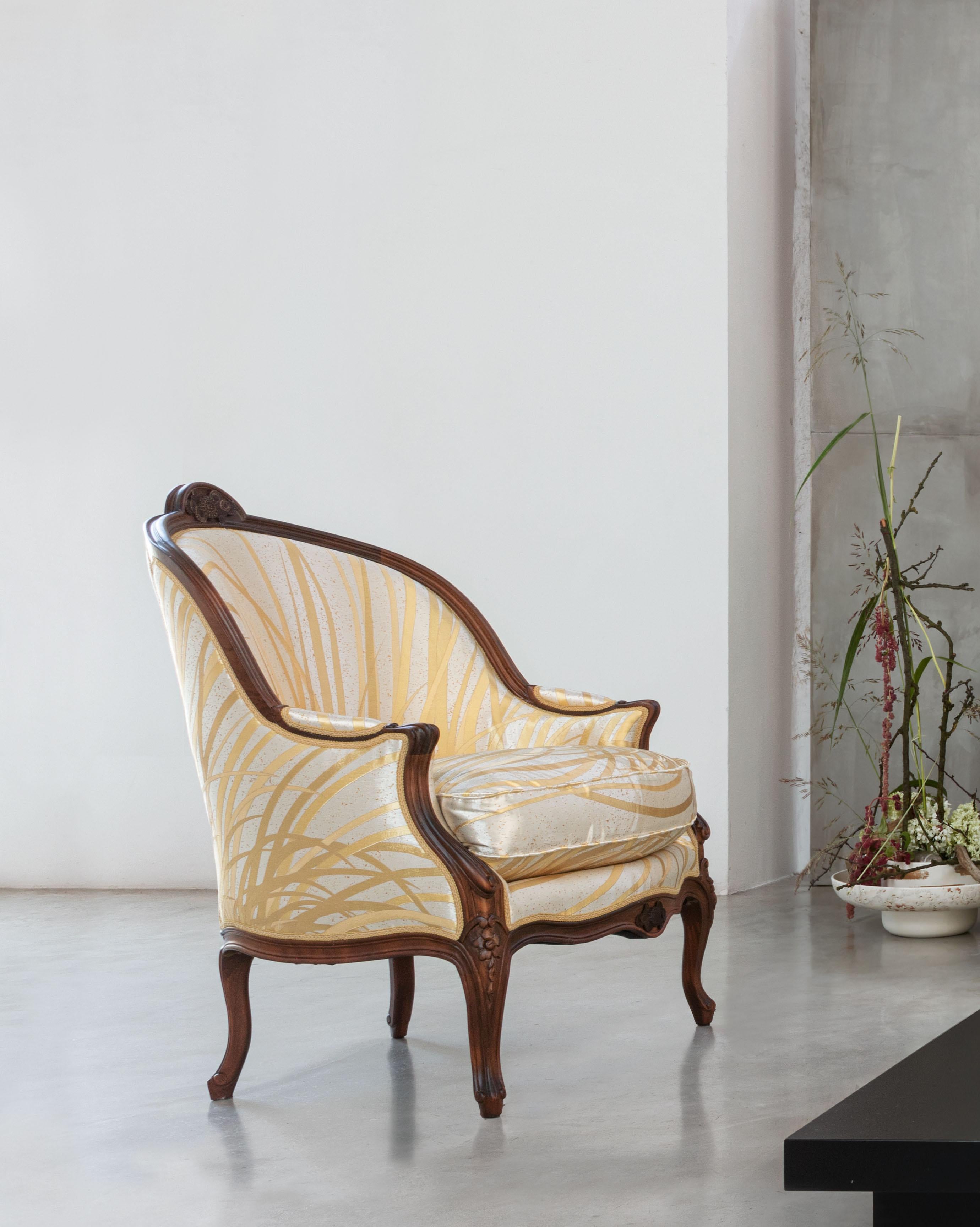 An exceptional work of craftsmanship by wood and textile artisans, this plush armchair is a charming addition to refined modern interiors. Hand-carved from solid beech and finished in an antique walnut hue, its structure is padded with