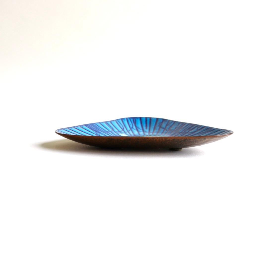 A wonderful enameled triangle shaped copper plate by Annemarie Davidson of Sierra Madre. The design features incised rays emanating from the famous jewel-like structures offset from the center of plate. This pattern is sometimes known as
