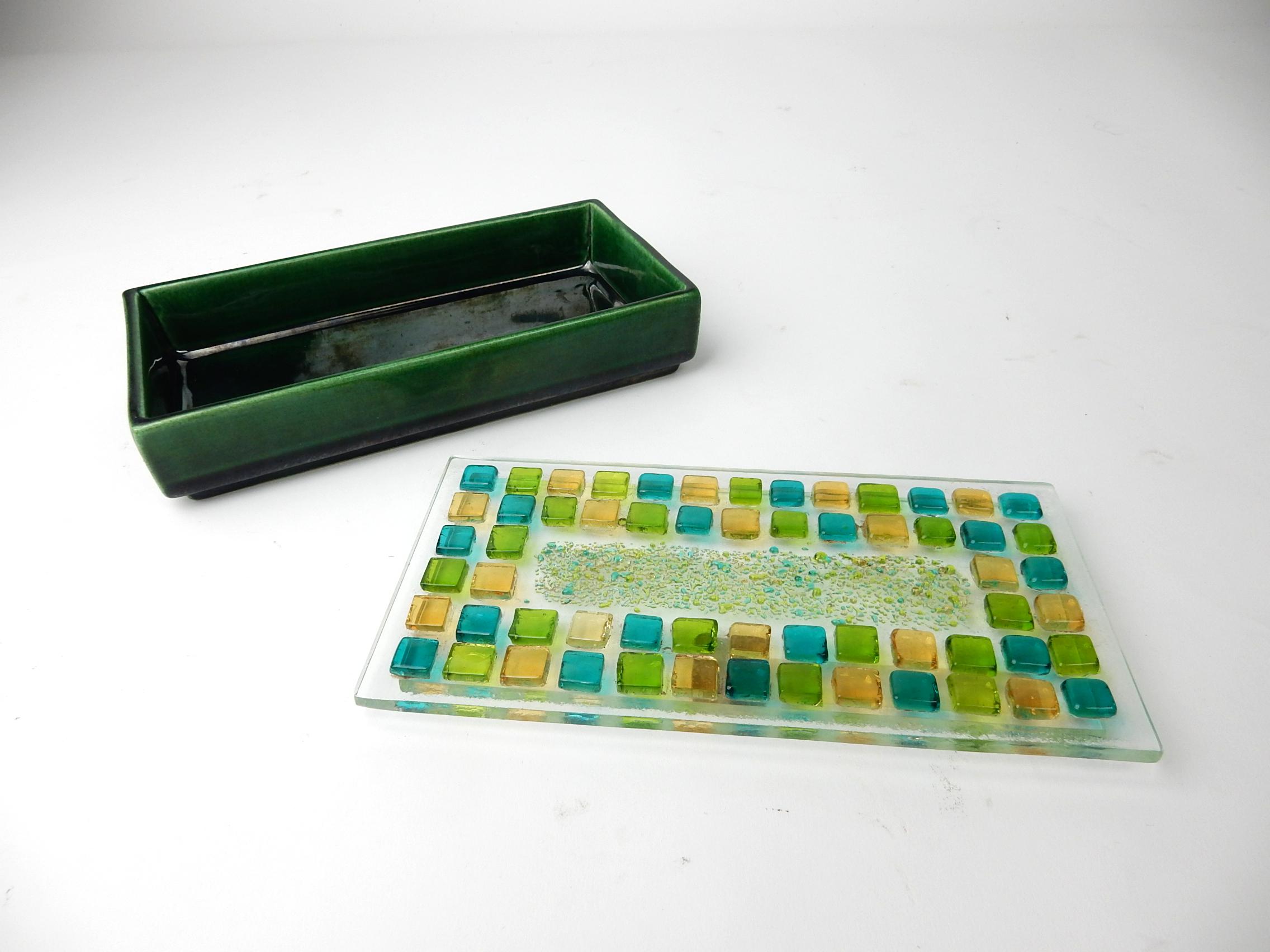 A perfect coffee table display this circa 1960s art glass smoking set by Annette Behre' of California.
Gorgeous set consisting of a fused blue, green and orange glass gem lid on a green ceramic box
with a blue/green swirl art glass ashtray to