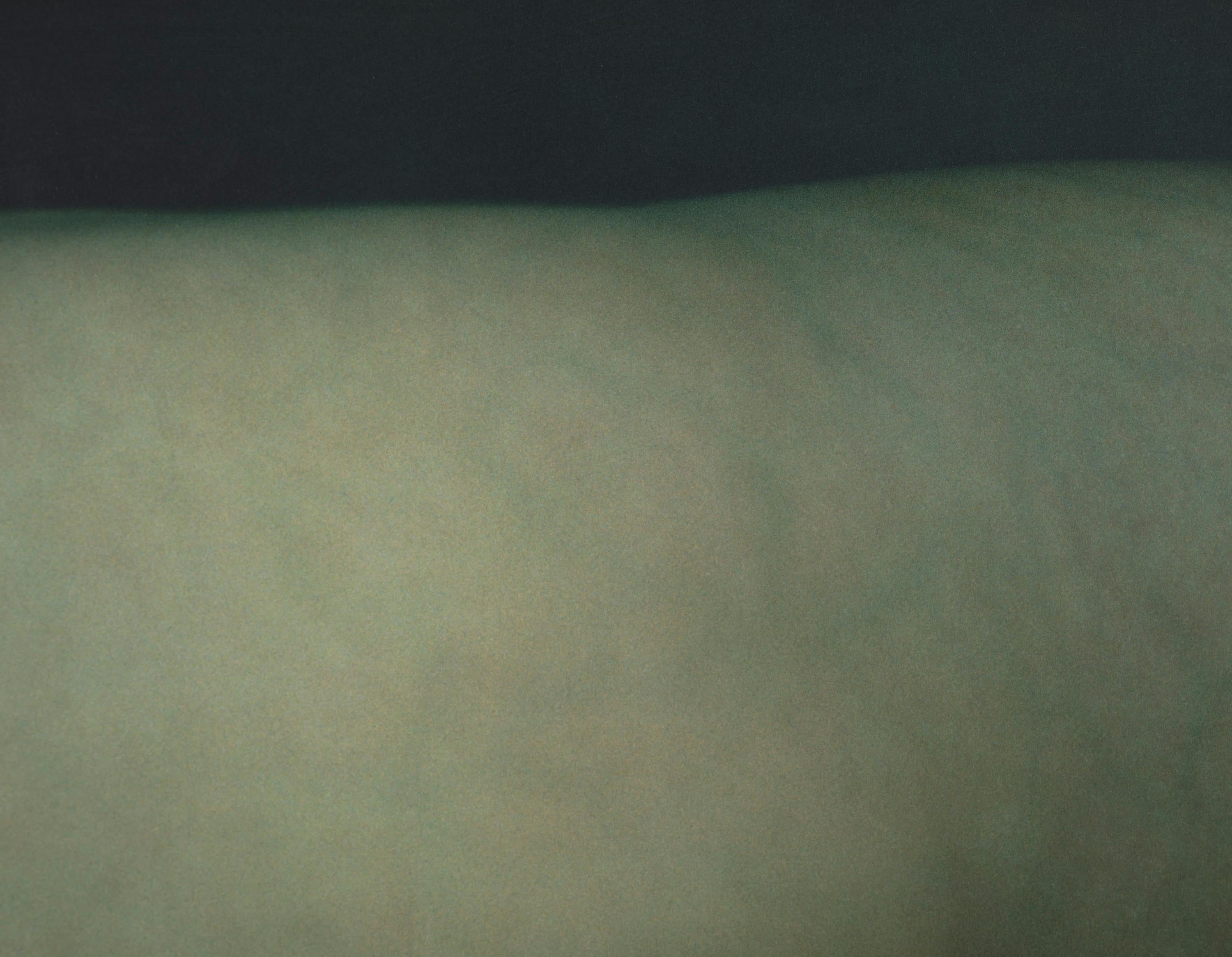 This nude portrait by famed fashion photographer Annie Leibovitz creates an abstracted view of the figure with its close-up composition. The cool blue and green hues are complimented by the dark blue background which also highlights the female