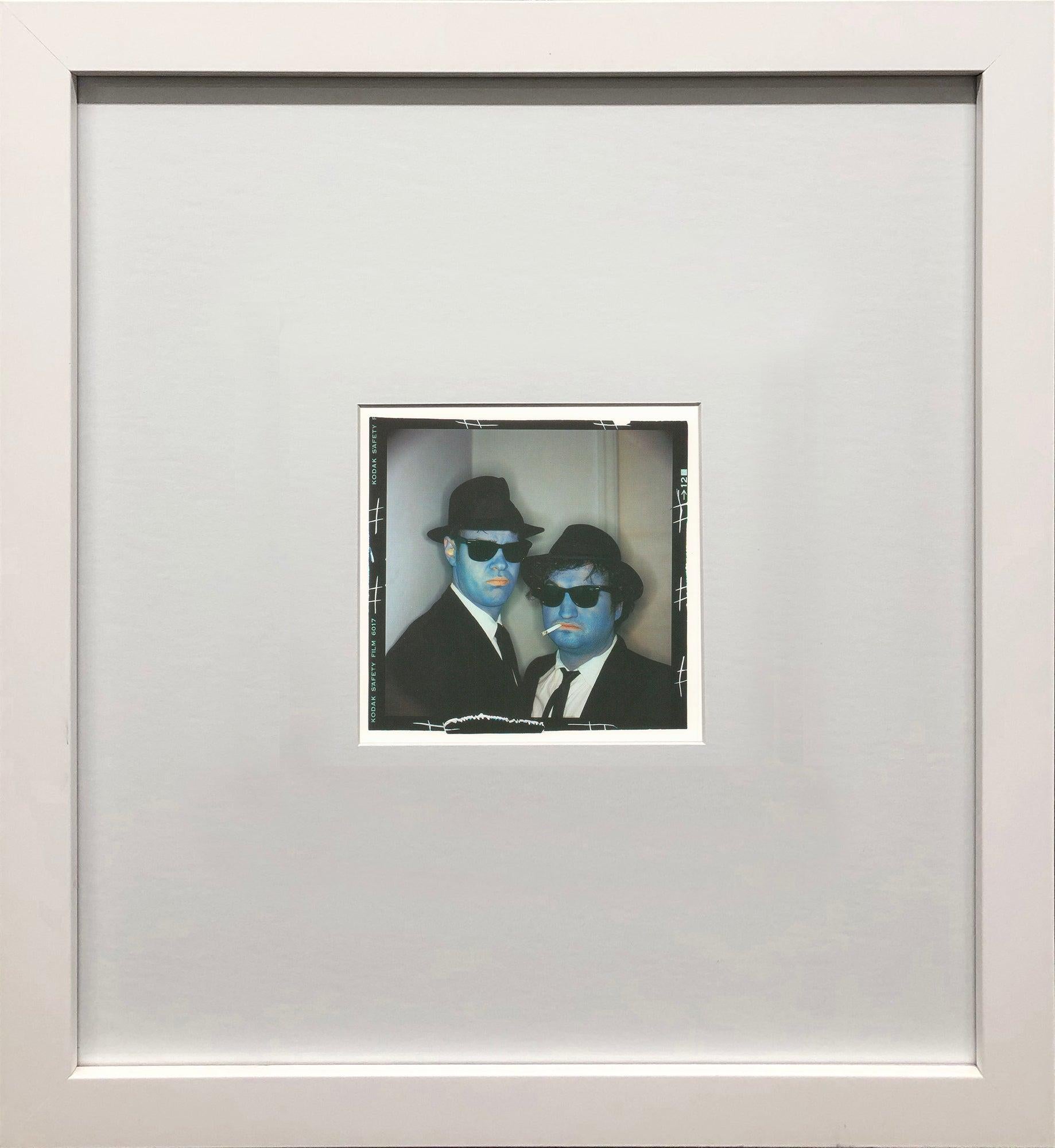 Cette pièce encadrée présente une image emblématique de la célèbre photographe Annie Leibovitz, représentant son fameux portrait de John Belushi et Dan Aykroyd. Capturée avec la signature visuelle et la composition dramatique de Leibovitz, la