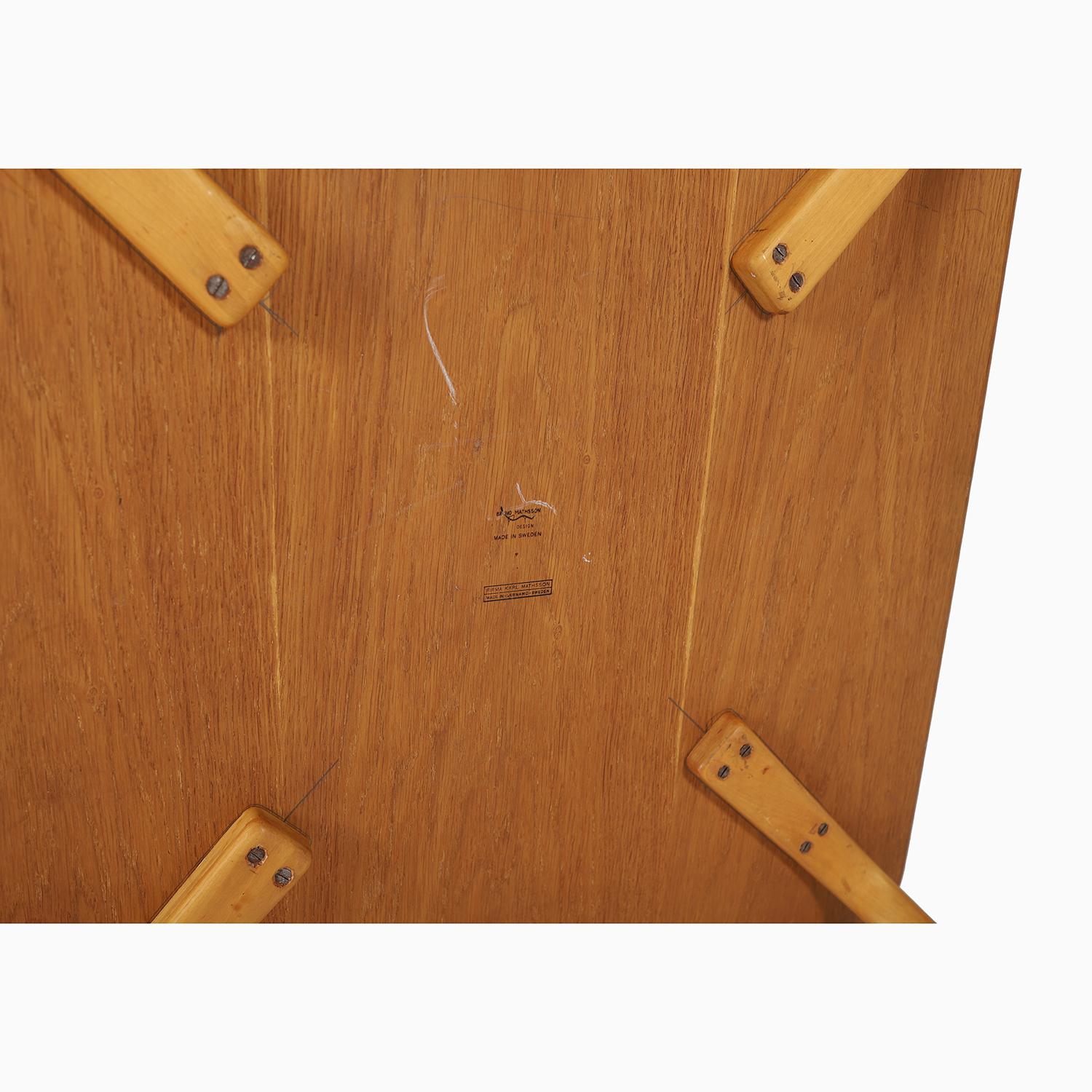 Une table sexy, élégante et éternellement stylée avec un plateau en teck et de magnifiques pieds en hêtre.  Cette table a été conçue par le légendaire designer suédois Bruno Mathsson et produite par Karl Mathsson dans la Suède des années 1940.  

La