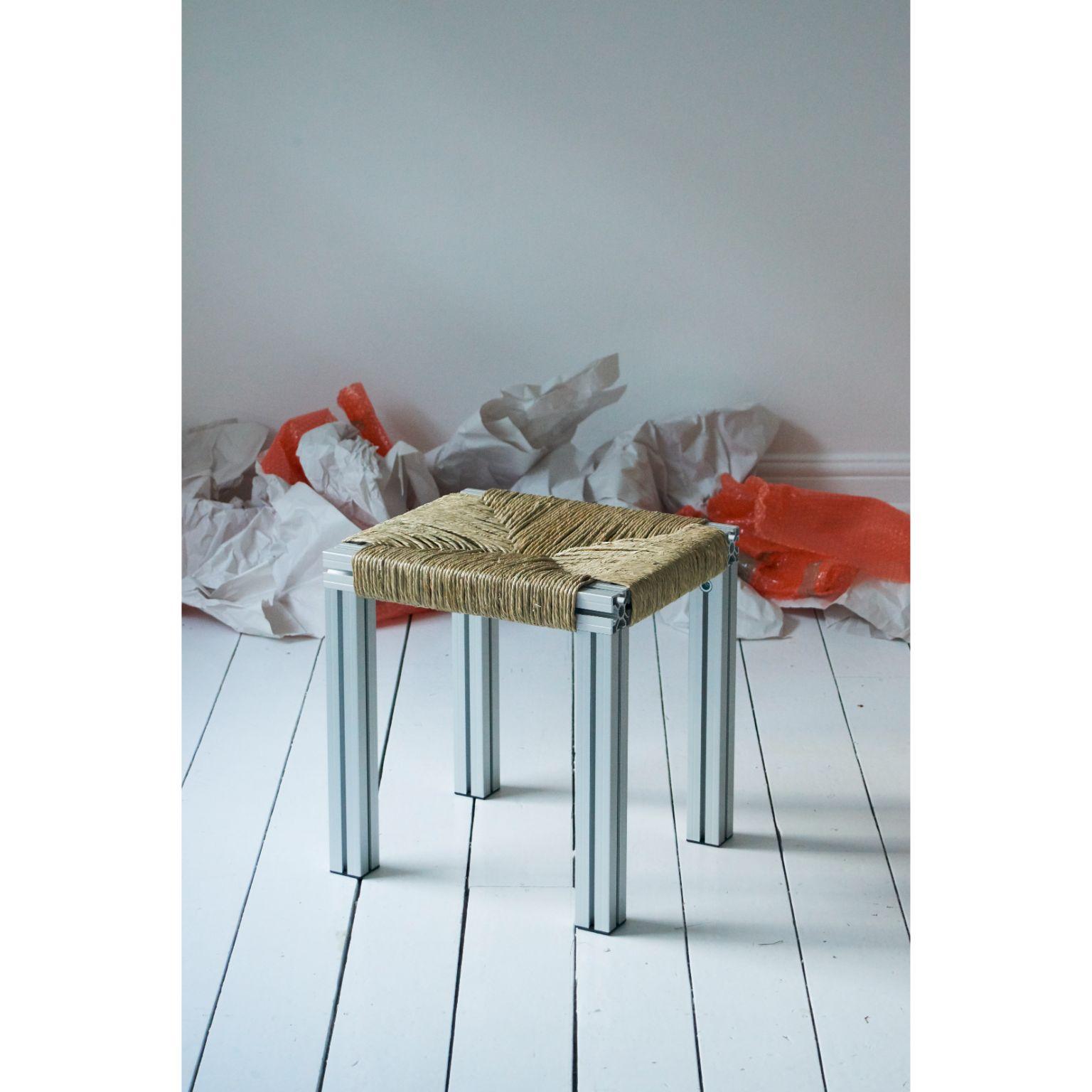 Anodized grey and rush weave wicker stool by Tino Seubert
Dimensions: D 43 x W 38 x H 45 cm.
Materials: Grey anodised aluminum extrusions, rush.

Tino Seubert
When he first made his now signature wicker and aluminium stools and benches in 2018