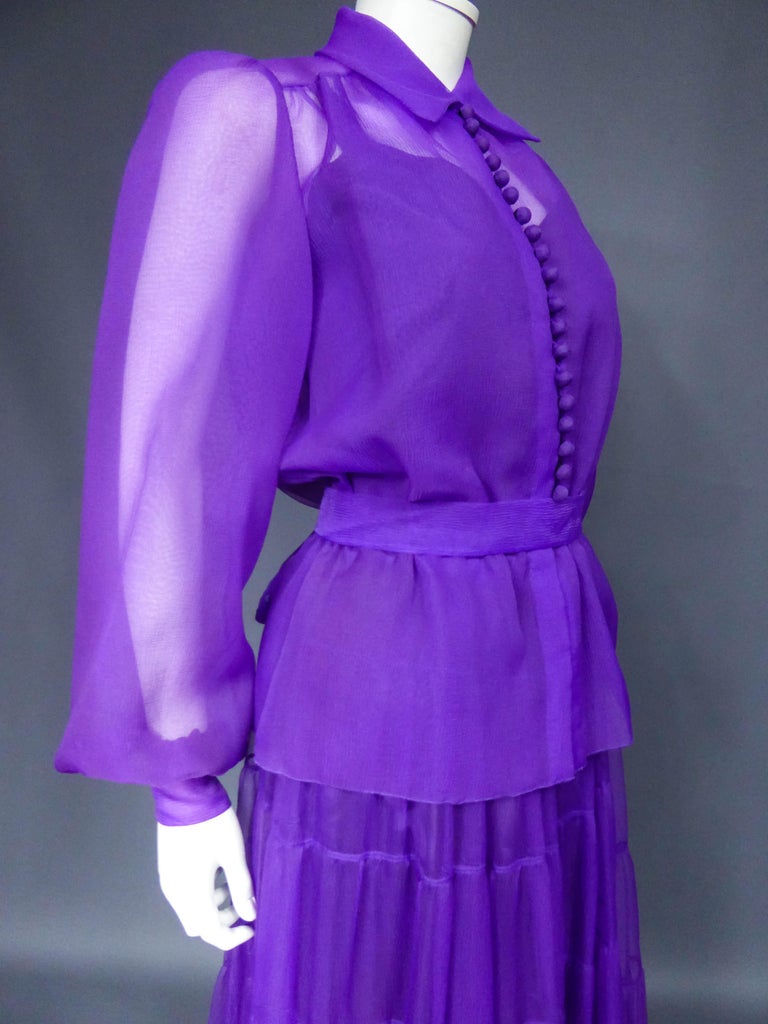 Circa 1970
France

Blouse, skirt and belt set in purple organza from the 1970s. Blouse with puffed sleeves adorned with buttons in the same fabric, tightened at the waist by an elastic under the belt. Closing of the blouse at the front by buttons