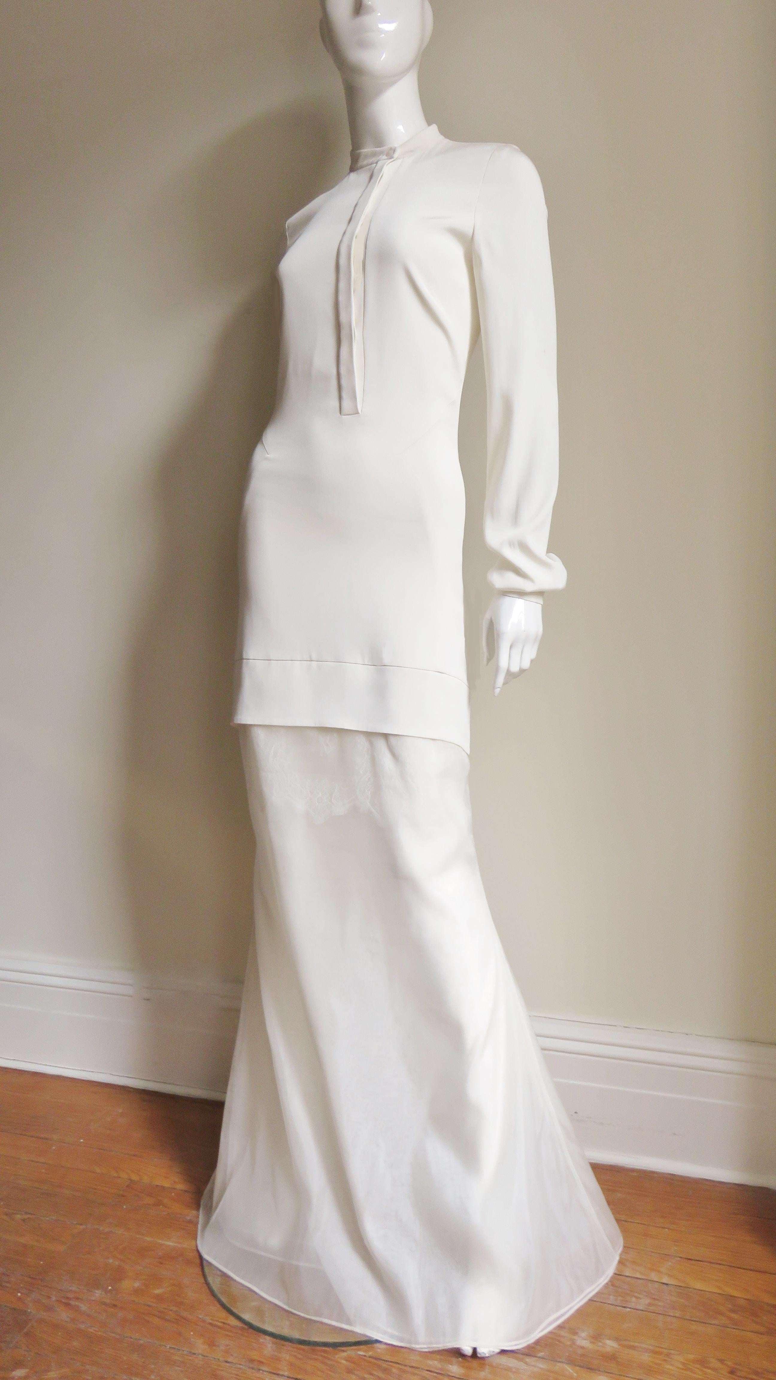 A gorgeous off white silk gown, maxi dress from Antonio Berardi.  It is semi fitted to above the knee, has a hidden front button placket and long sleeves with black center off white mother of pearl buttons on each cuff.  There are flattering diamond