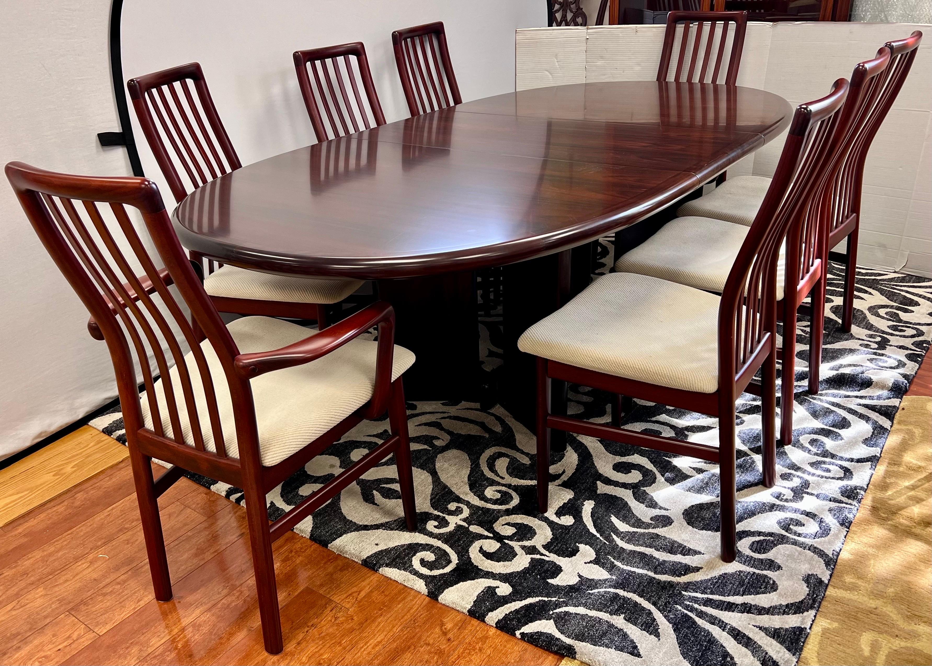 Danish modern rosewood dining set includes a pedestal dining table with two leaves and 8 chairs, 2 arms and 6 sides. The table is crafted from high-quality rosewood and features a sleek design,  Chairs are upholstered in a beige textured fabric.