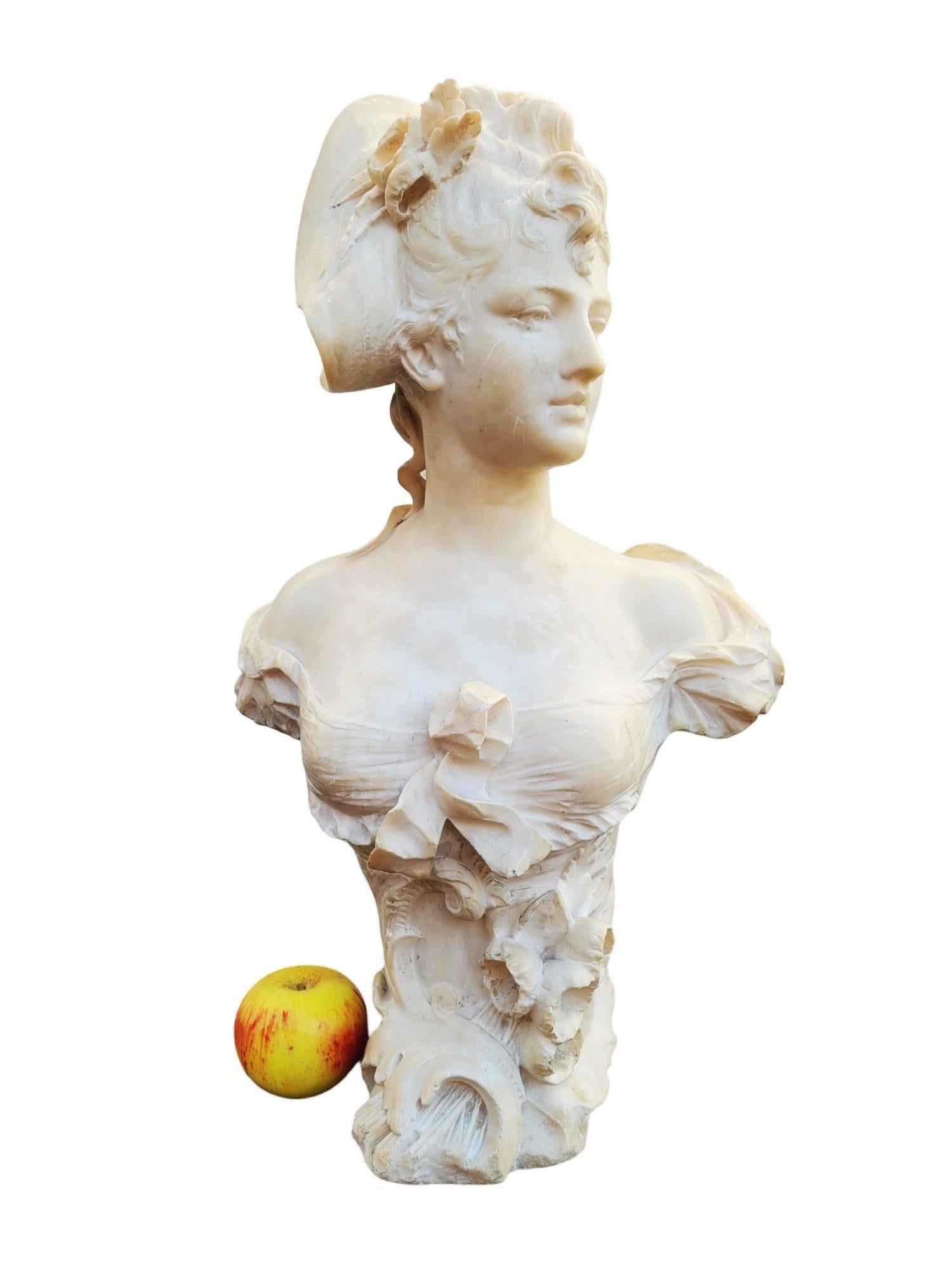 Bellissimo busto in alabastro di una donna elegante con un cappello e un nastro tra i capelli; la base è decorata con fiori/foglie

Questo busto è firmato sul retro Ant Nelson: questo è lo pseudonimo utilizzato dallo scultore belga Antoine Van Den