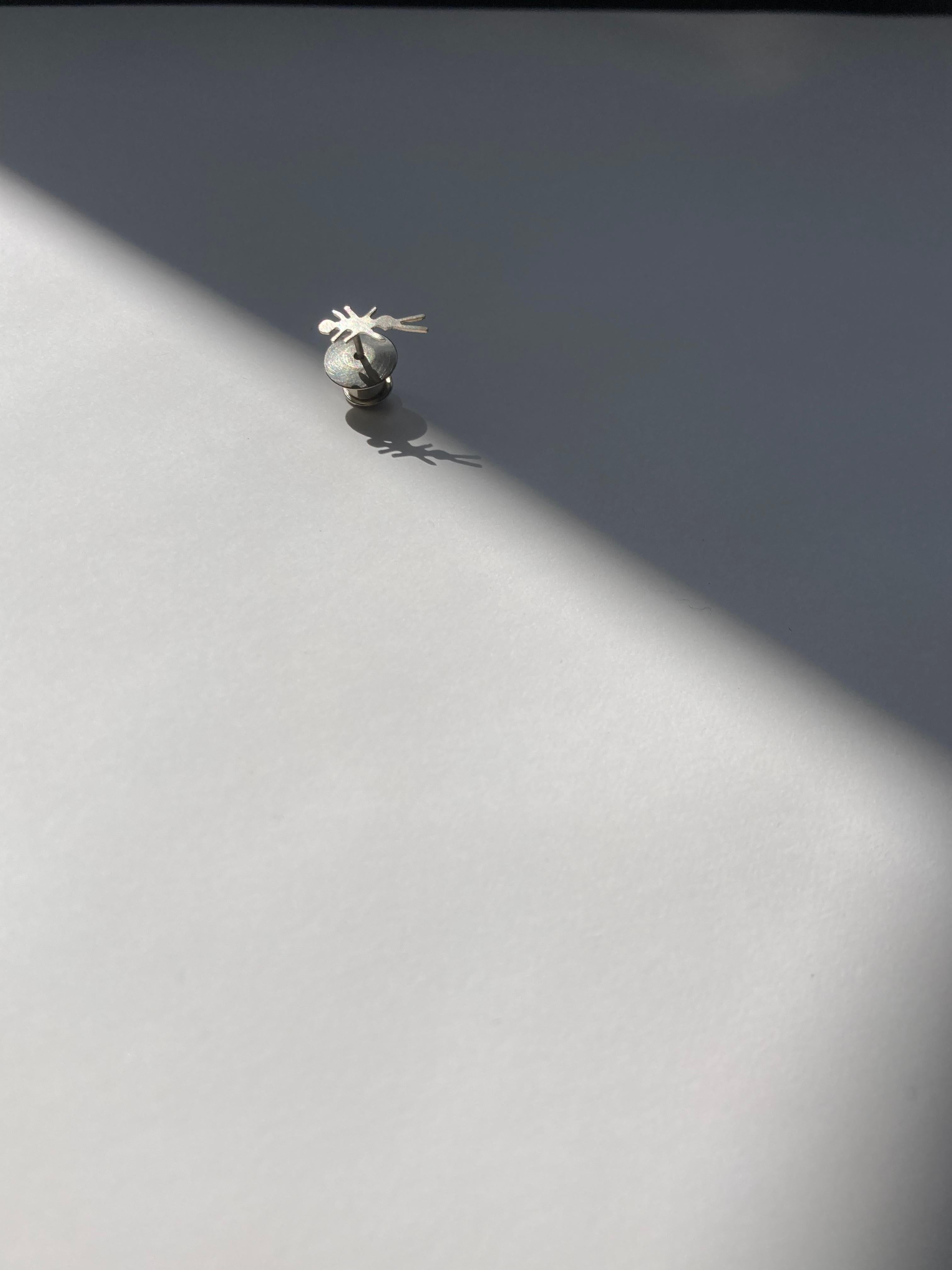 This playful ant pin is a subtle embellishment for your clothing. Great on a lapel, or perhaps scattered across a garment. 

It is hand cut by eye from sterling silver, and is finished with a matte sheen to subtly catch the light when worn. Each is