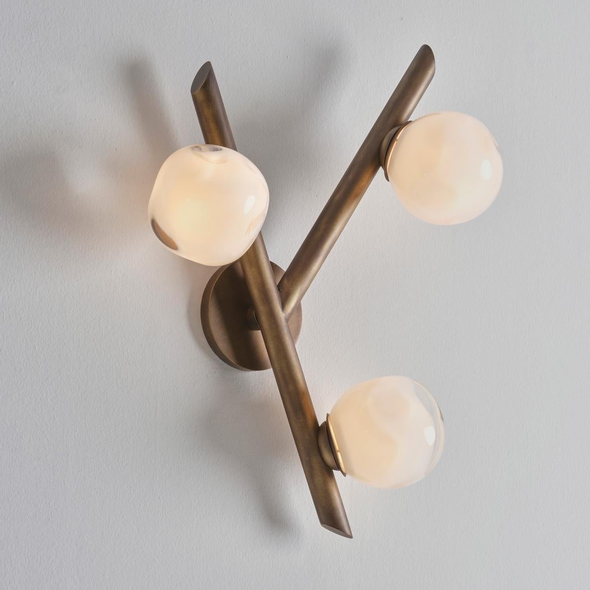 The Antares wall light harmoniously balances the linear details of its intersecting arms with the organic form of its handblown glass shades. The first images show the fixture in our Bronzo Nuvolato (bronze) finish-subsequent pictures show it in a