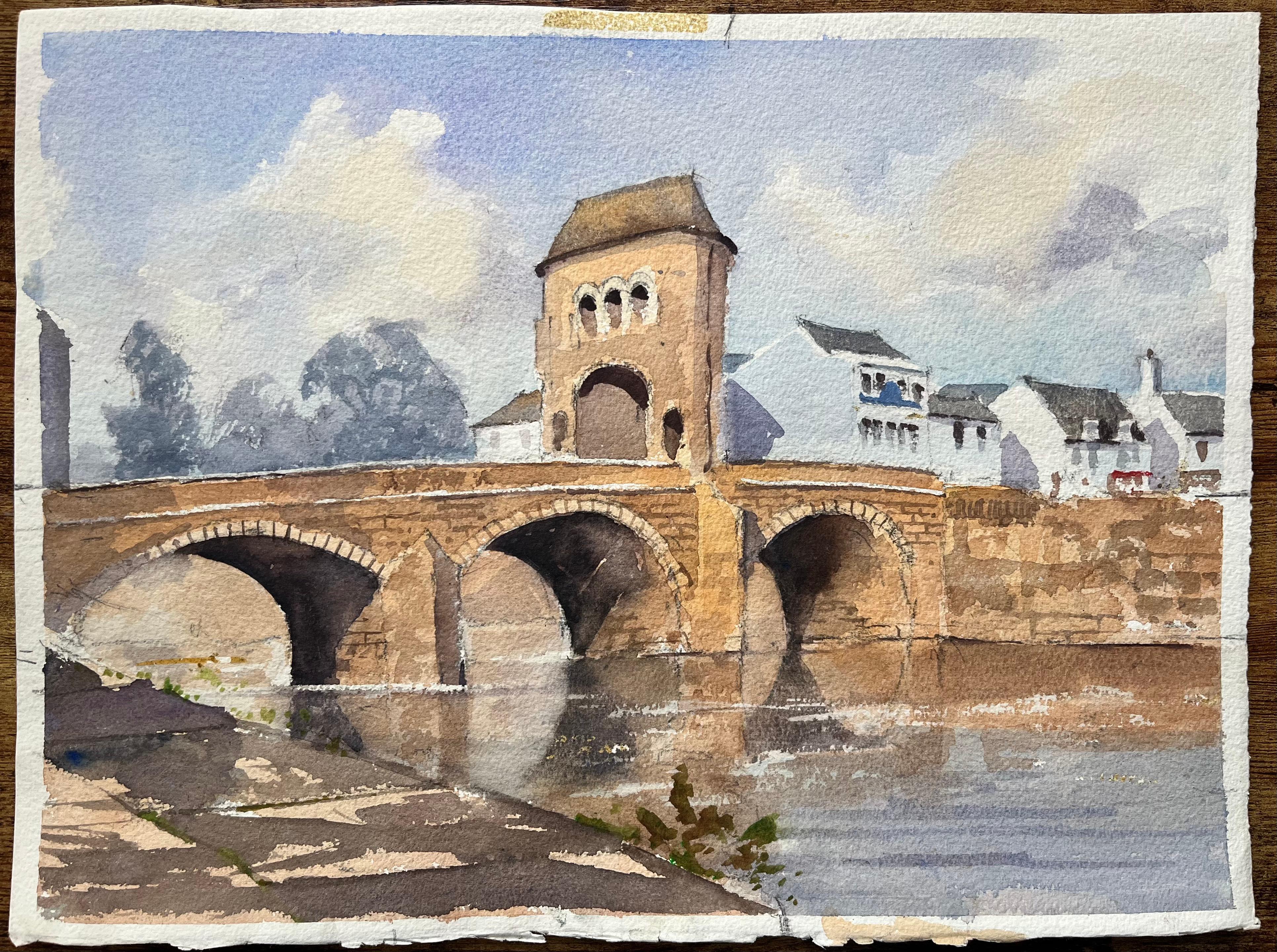 Acuarela impresionista británica de un puente de piedra iluminado por el sol y un pueblo ribereño - Painting de Anthony Avery