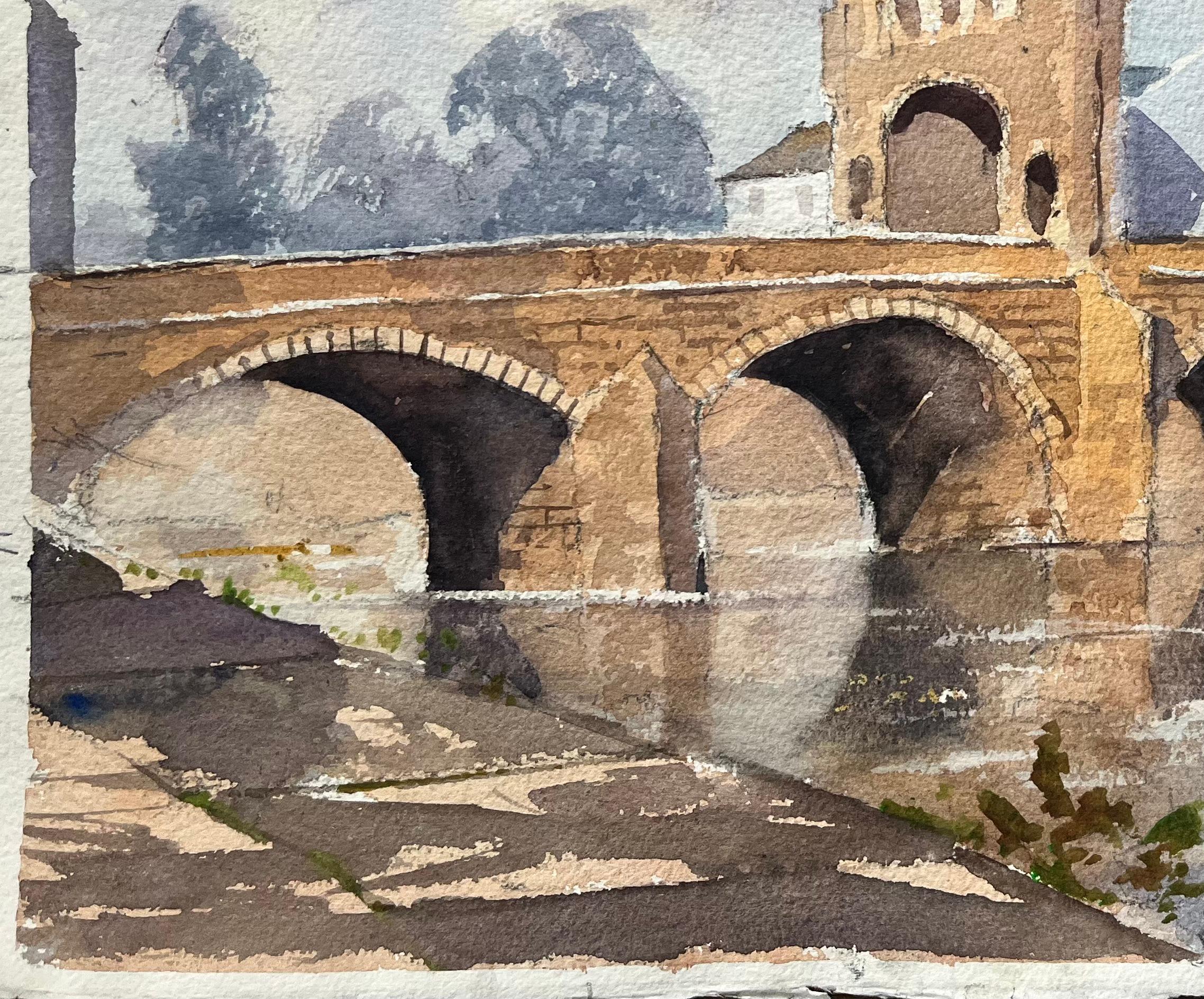 Acuarela impresionista británica de un puente de piedra iluminado por el sol y un pueblo ribereño - Landscape Painting Gris de Anthony Avery