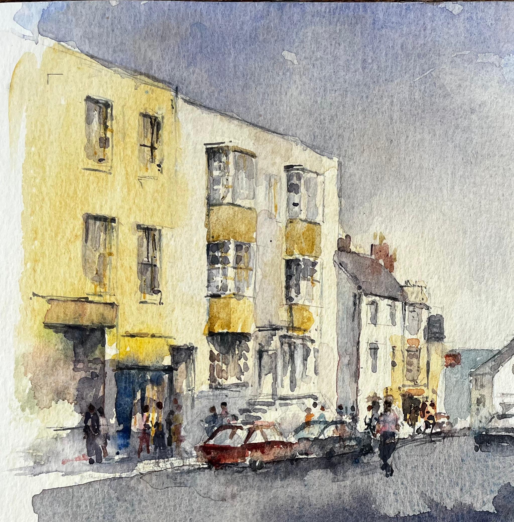 Titel: Belebte Hauptstraße mit Figuren, Autos und gelben Stadthäusern Aquarell
Von Tony Herbert (1927-2024)
Signiert unten links
Medium: Aquarell auf Künstlerpapier
Größe: 10,25 x 13,5 Zoll 
Zustand: Insgesamt gut; ein paar schwache