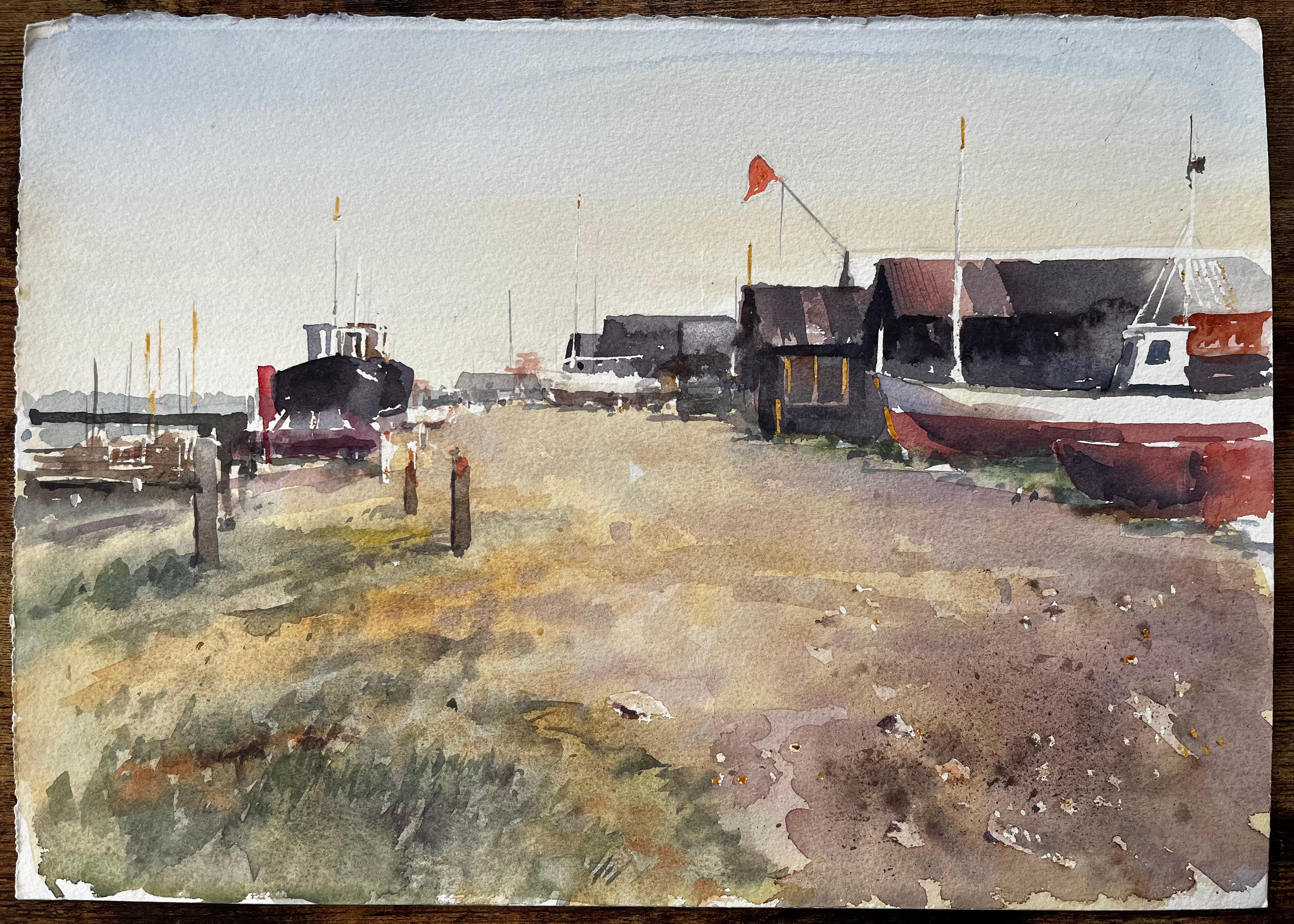 Küstenwerft mit Fischerhütten, gestrandeten Booten und roter Flagge Aquarellszene – Art von Anthony Herbert